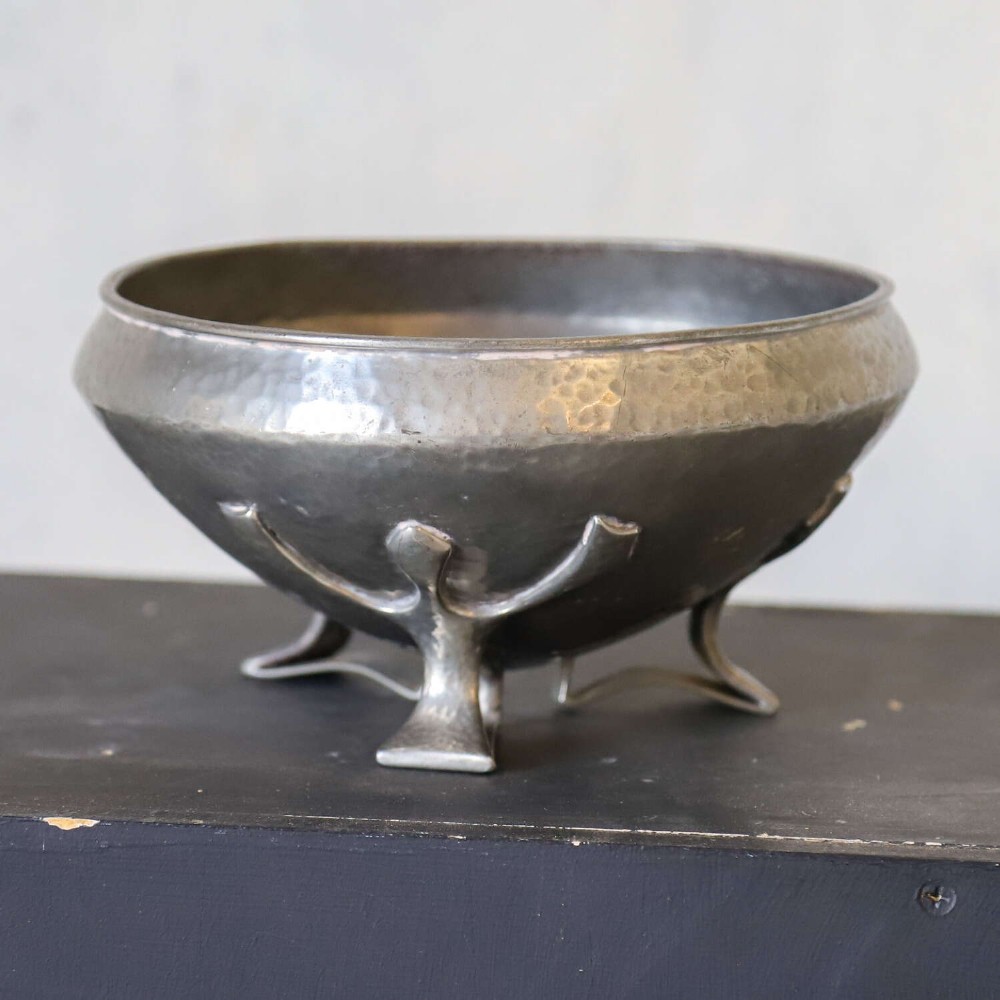 A hand-hammered grey pewter bowl featuring an inverted conical shape supported by stylised organic three-point legs. View VI
