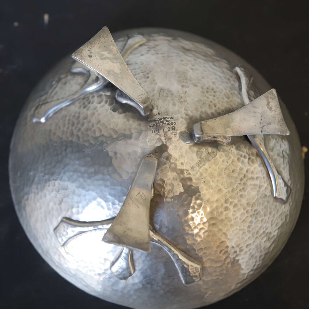 A hand-hammered grey pewter bowl featuring an inverted conical shape supported by stylised organic three-point legs. View VII