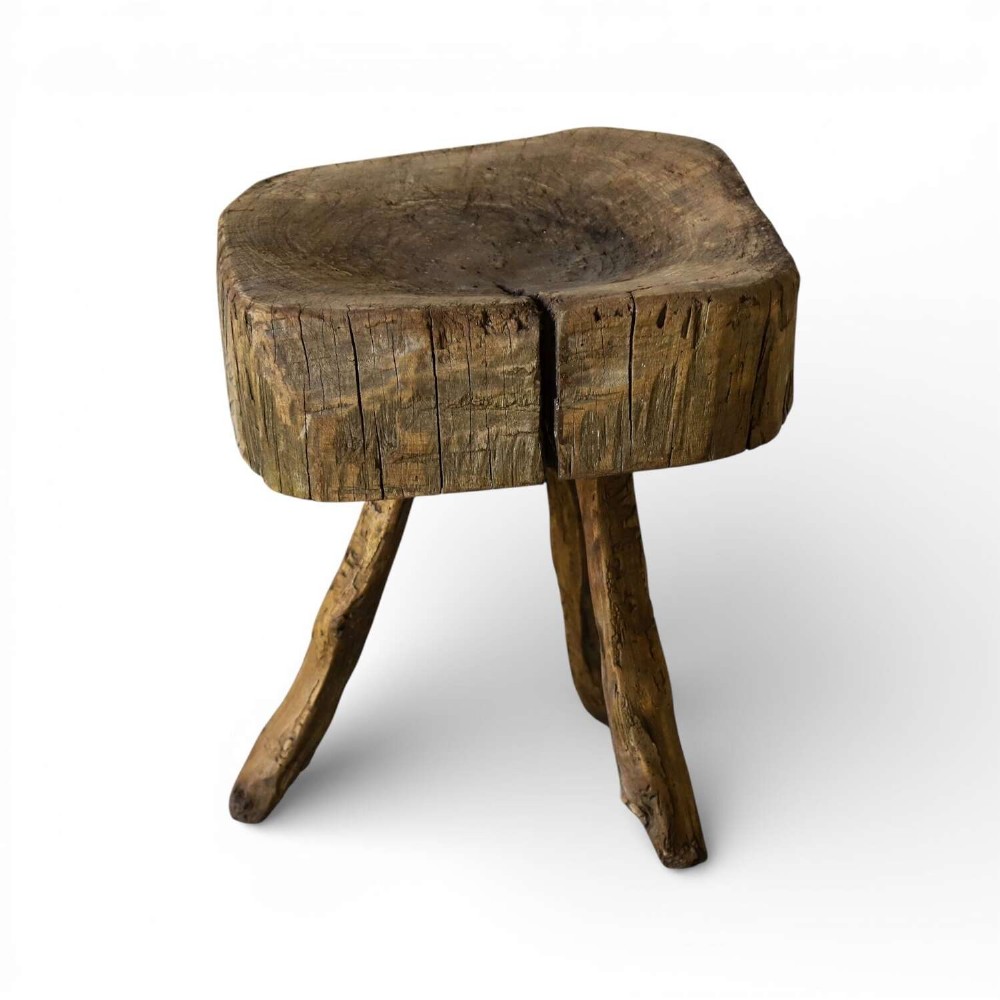 A 19th-century French elm chopping block featuring a heavy carved wooden top supported by three natural gnarled legs.