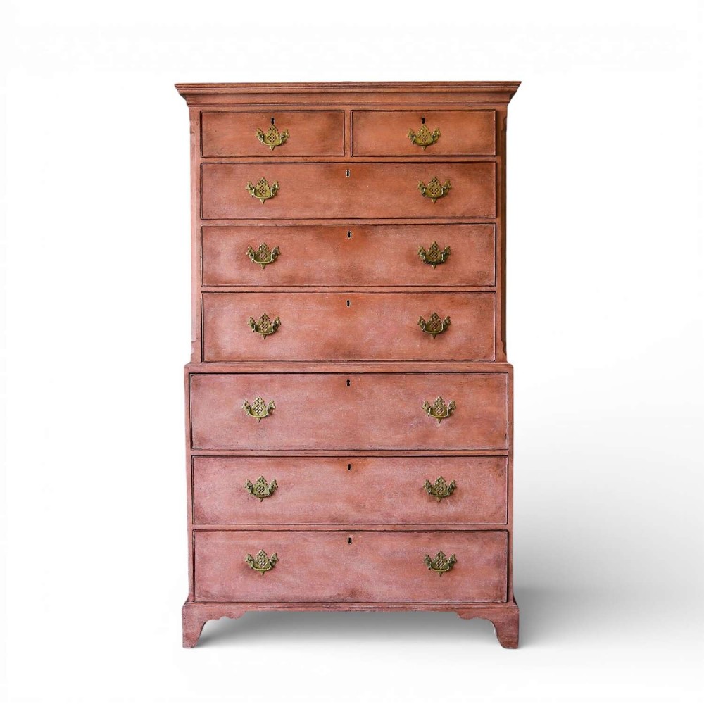 An eighteenth-century Georgian chest on chest with a distressed terracotta painted finish, brass pierced handles, and bracket feet.