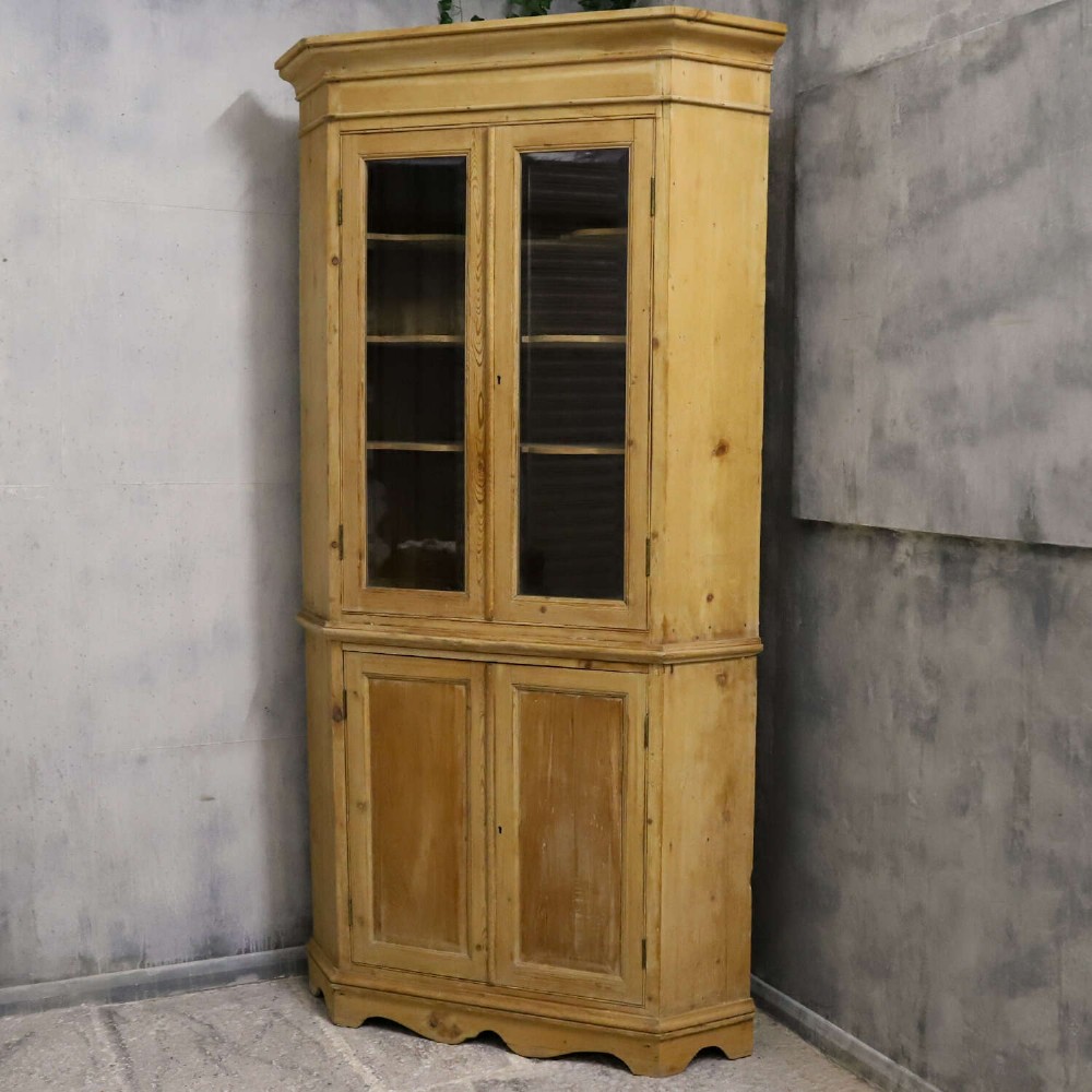 A nineteenth-century two-part pine corner cupboard featuring glazed upper doors and panelled lower doors with a shaped apron. View II