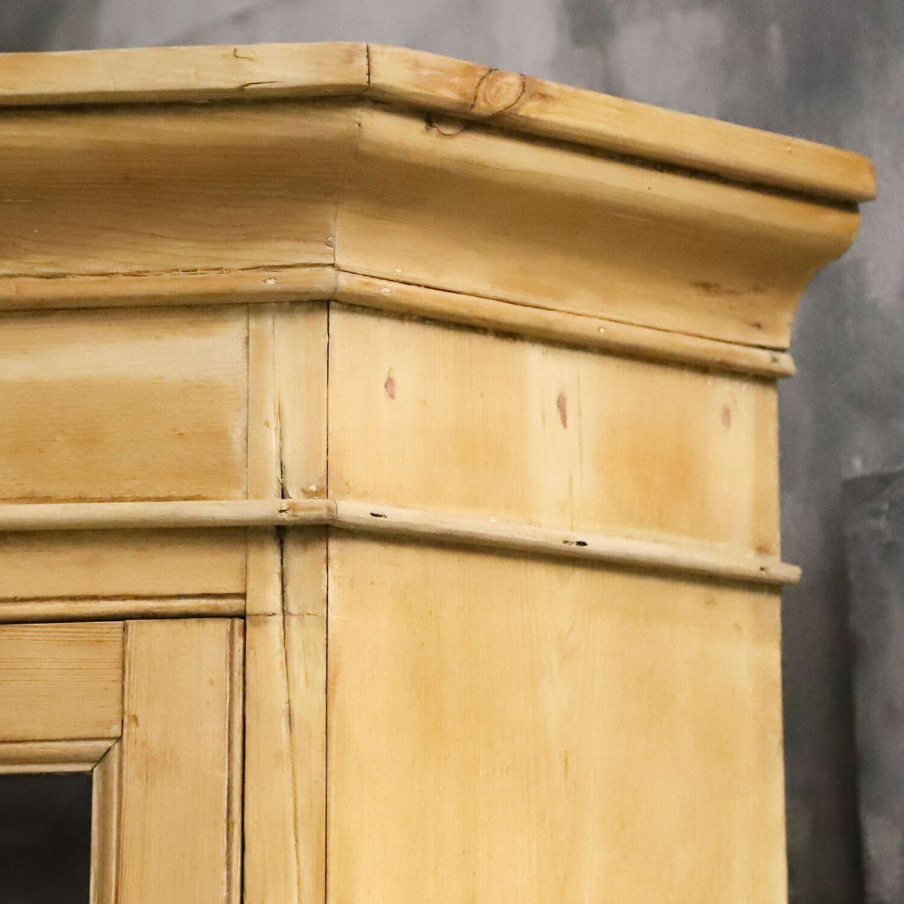A nineteenth-century two-part pine corner cupboard featuring glazed upper doors and panelled lower doors with a shaped apron. View IV