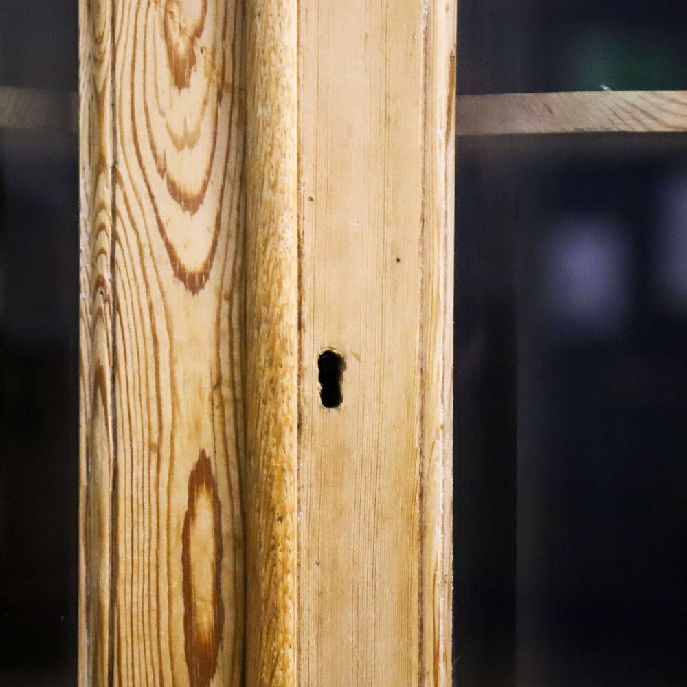 A nineteenth-century two-part pine corner cupboard featuring glazed upper doors and panelled lower doors with a shaped apron. View VII