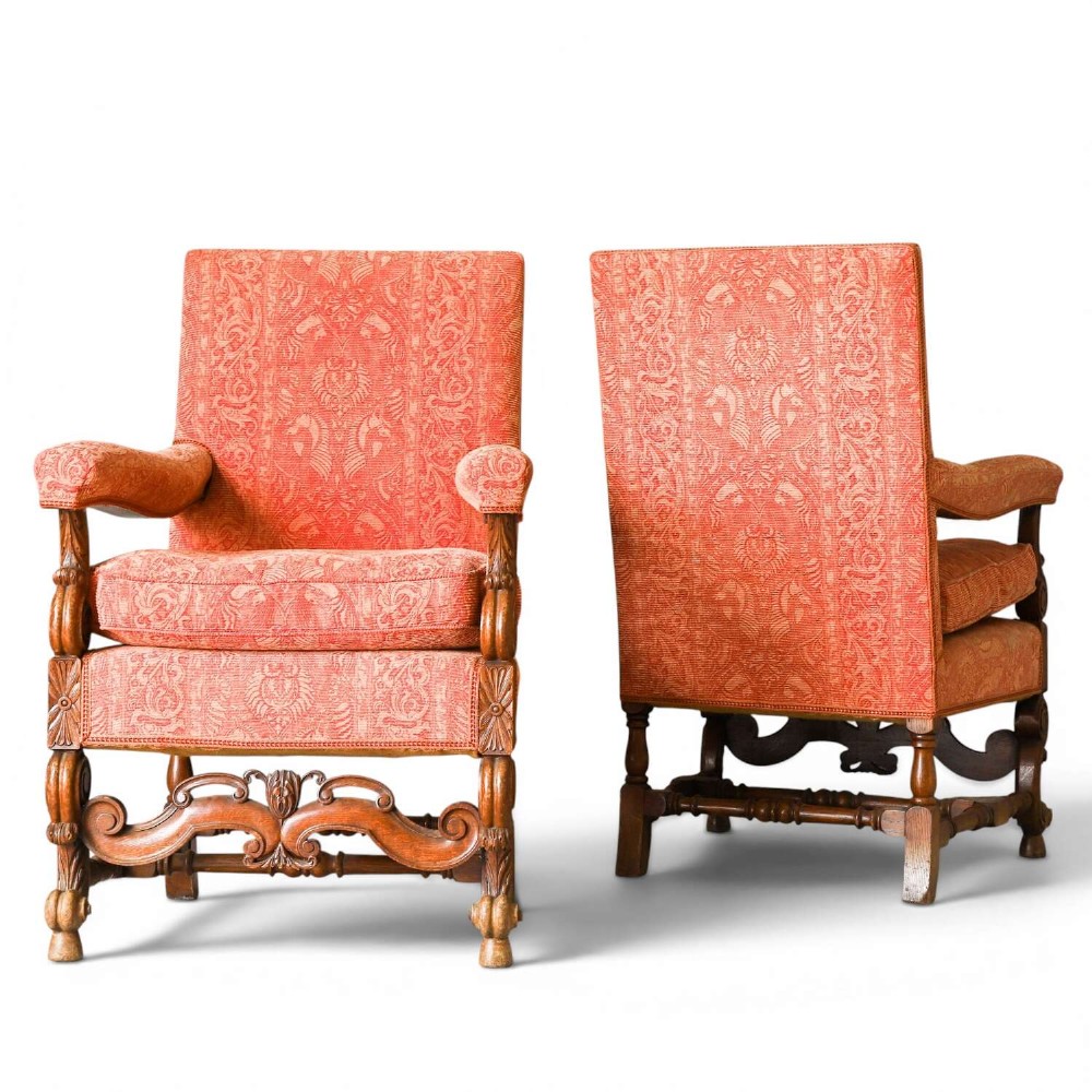 A pair of late nineteenth-century French Renaissance Revival oak armchairs upholstered in terracotta patterned fabric with carved scrolled stretchers and turned legs.