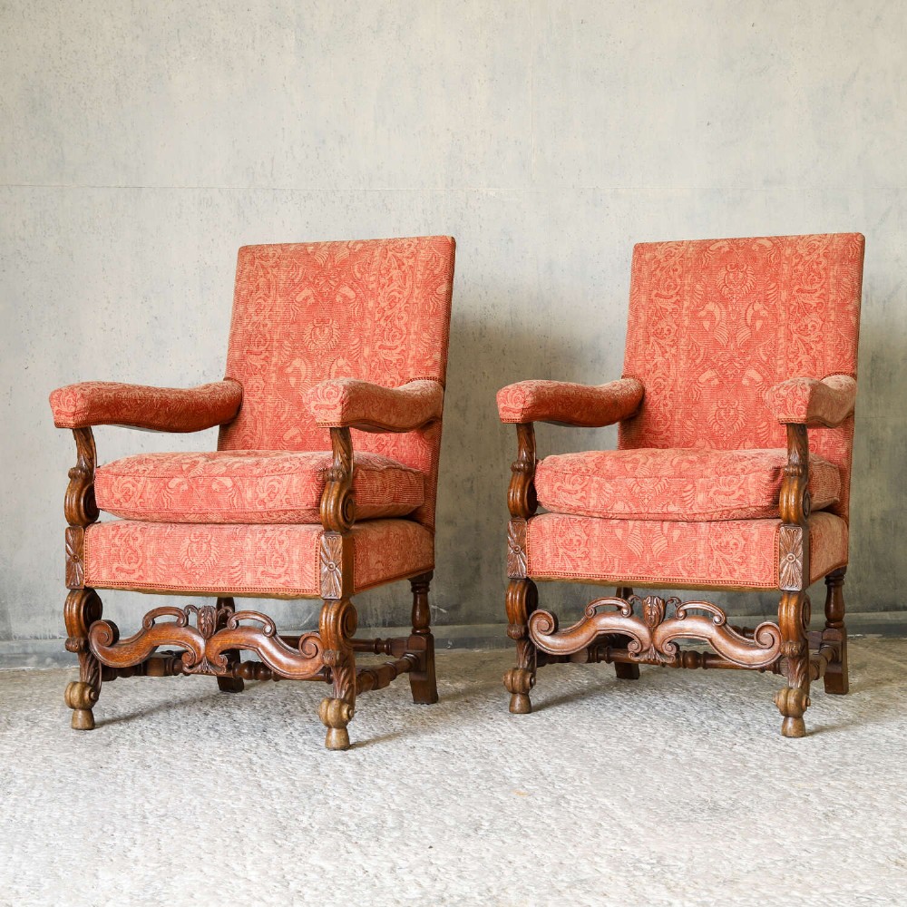 A pair of late nineteenth-century French Renaissance Revival oak armchairs upholstered in terracotta patterned fabric with carved scrolled stretchers and turned legs. View V