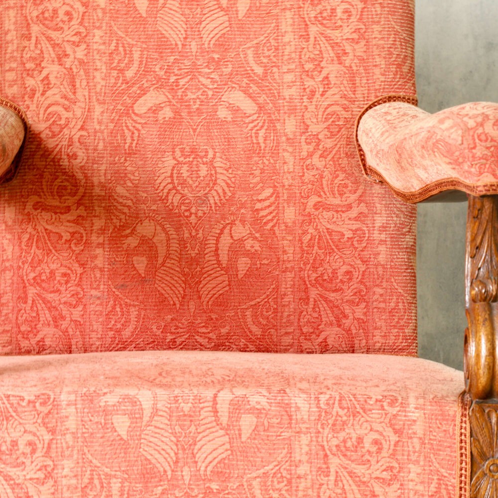 A pair of late nineteenth-century French Renaissance Revival oak armchairs upholstered in terracotta patterned fabric with carved scrolled stretchers and turned legs. View X