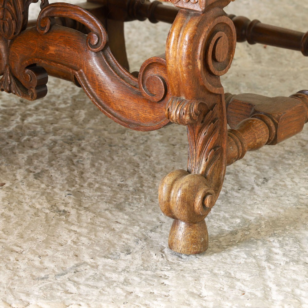 A pair of late nineteenth-century French Renaissance Revival oak armchairs upholstered in terracotta patterned fabric with carved scrolled stretchers and turned legs. View XIII