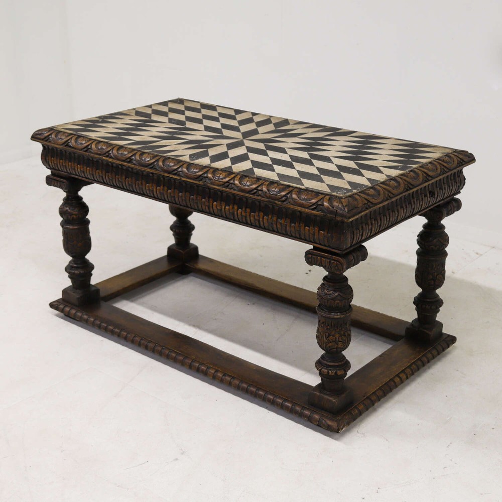 A 19th-century carved oak centre table featuring turned baluster legs, a stretcher base, and a geometric black and white painted starburst top. View II