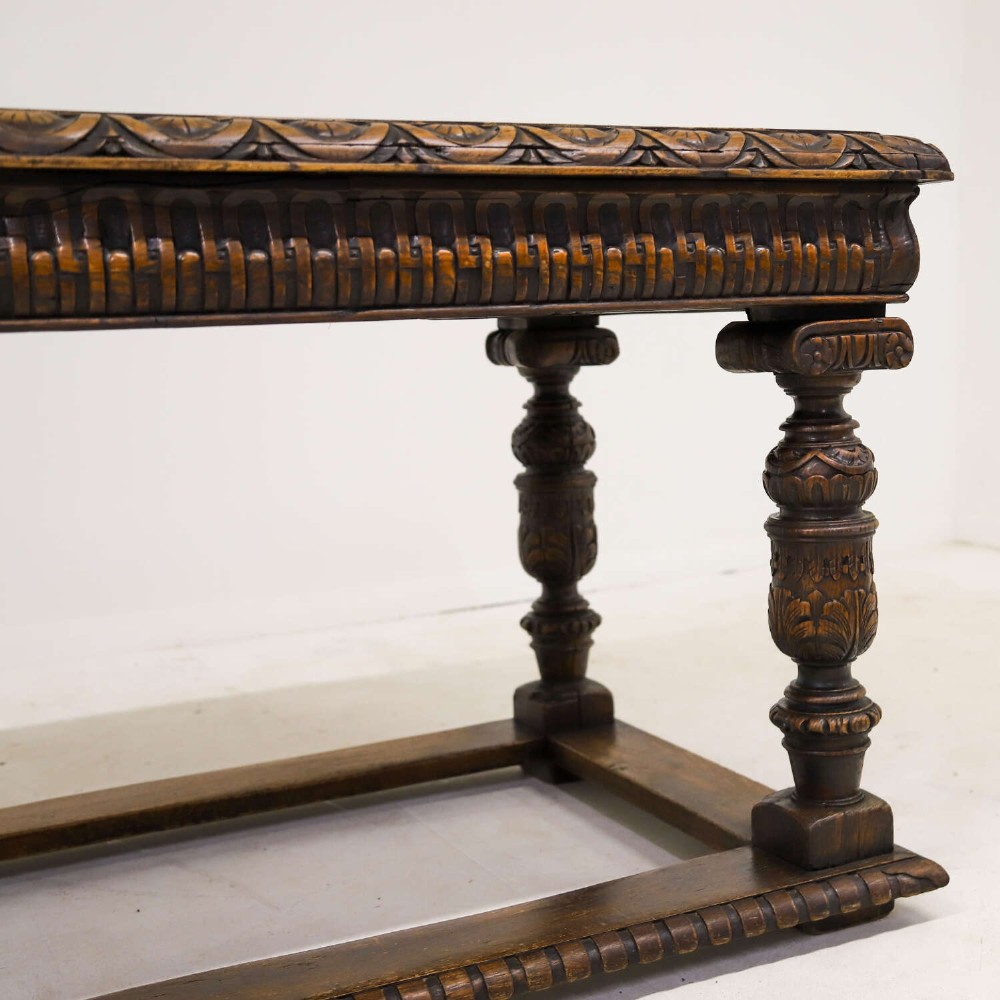 A 19th-century carved oak centre table featuring turned baluster legs, a stretcher base, and a geometric black and white painted starburst top. View VI