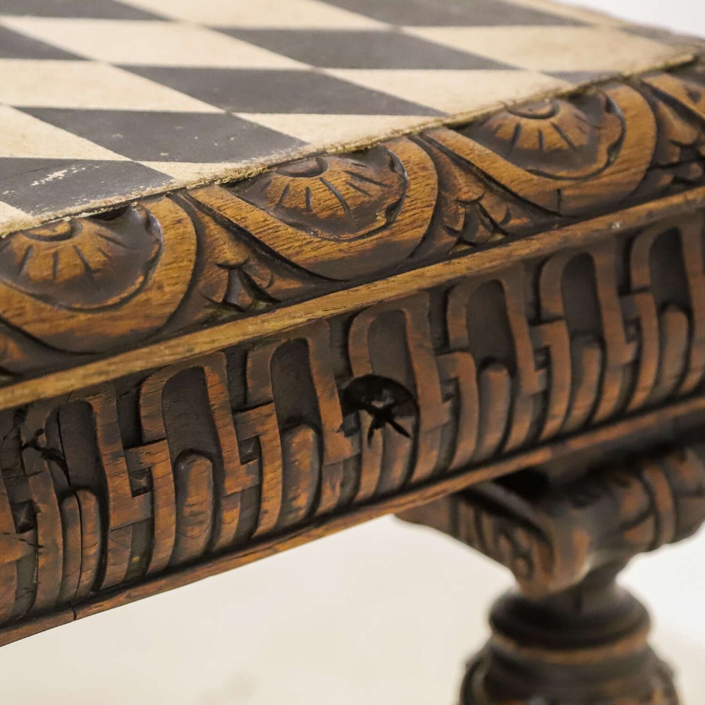 A 19th-century carved oak centre table featuring turned baluster legs, a stretcher base, and a geometric black and white painted starburst top. View IX