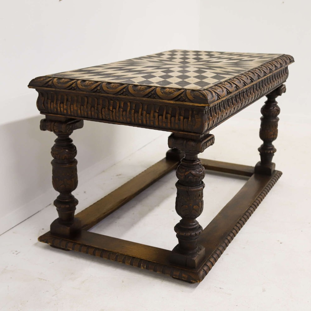 A 19th-century carved oak centre table featuring turned baluster legs, a stretcher base, and a geometric black and white painted starburst top. View XII