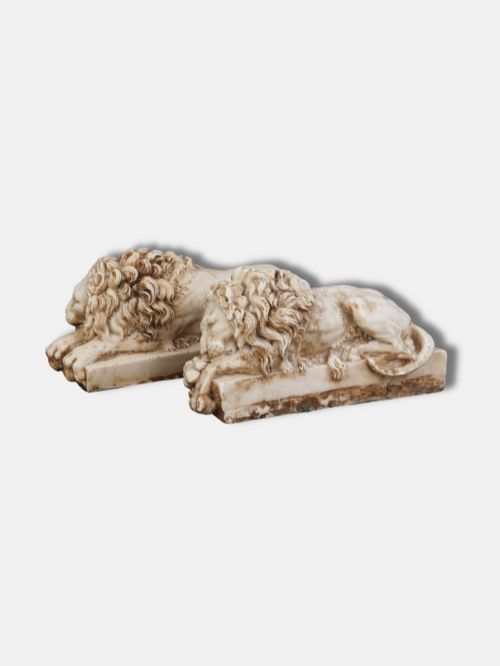 fig 1. A pair of carved off-white alabaster recumbent lions resting on rectangular plinths, crafted after Antonio Canovas original designs.