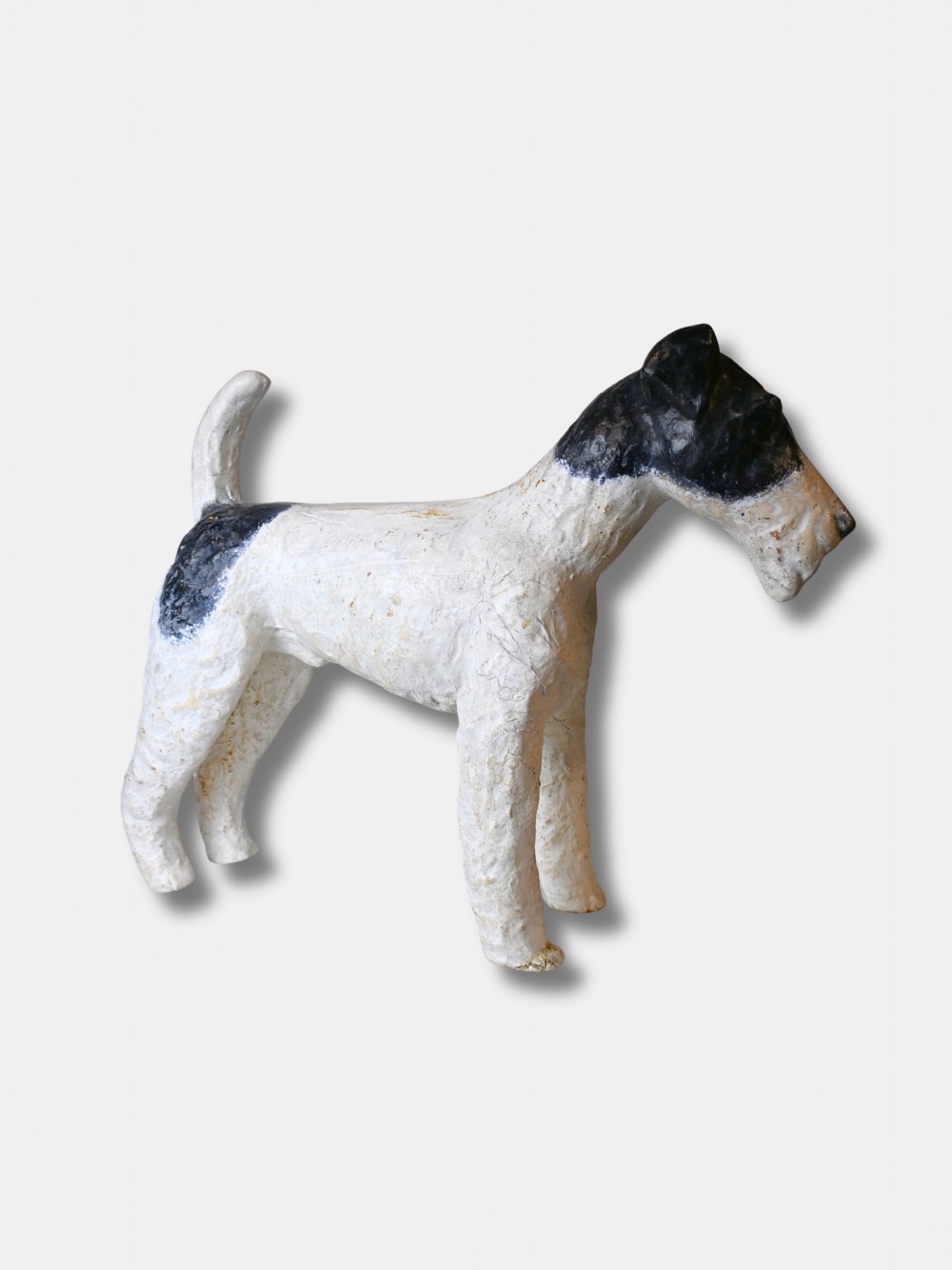 A life-size 1920s composition figure of a Fox Terrier featuring an off-white body, black painted markings on the head and back, and the name Osmond impressed into the shoulder. View II