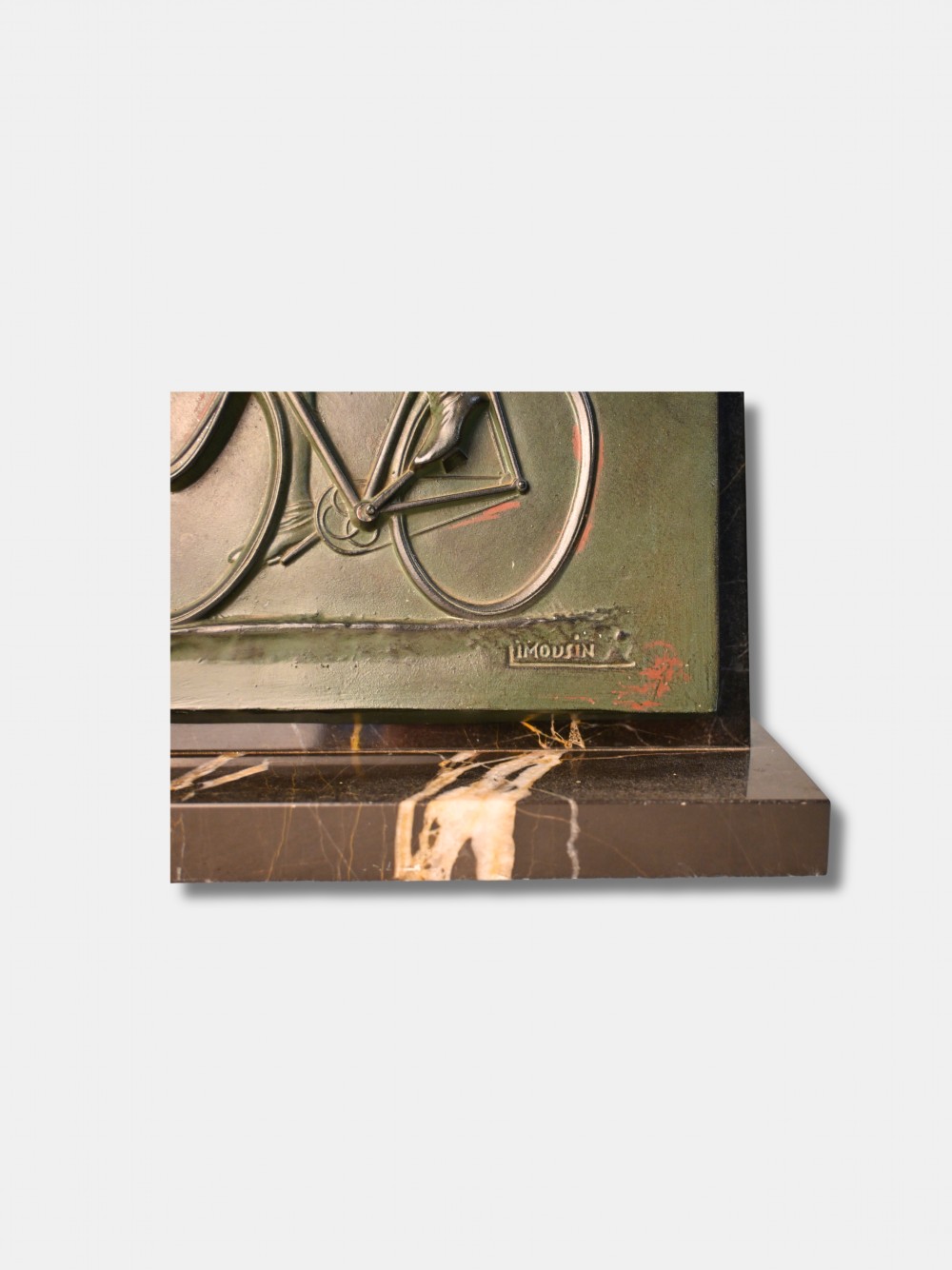 An Art Deco green patinated spelter relief sculpture depicting a cyclist leaning over handlebars, mounted on a veined black onyx plinth. View IV