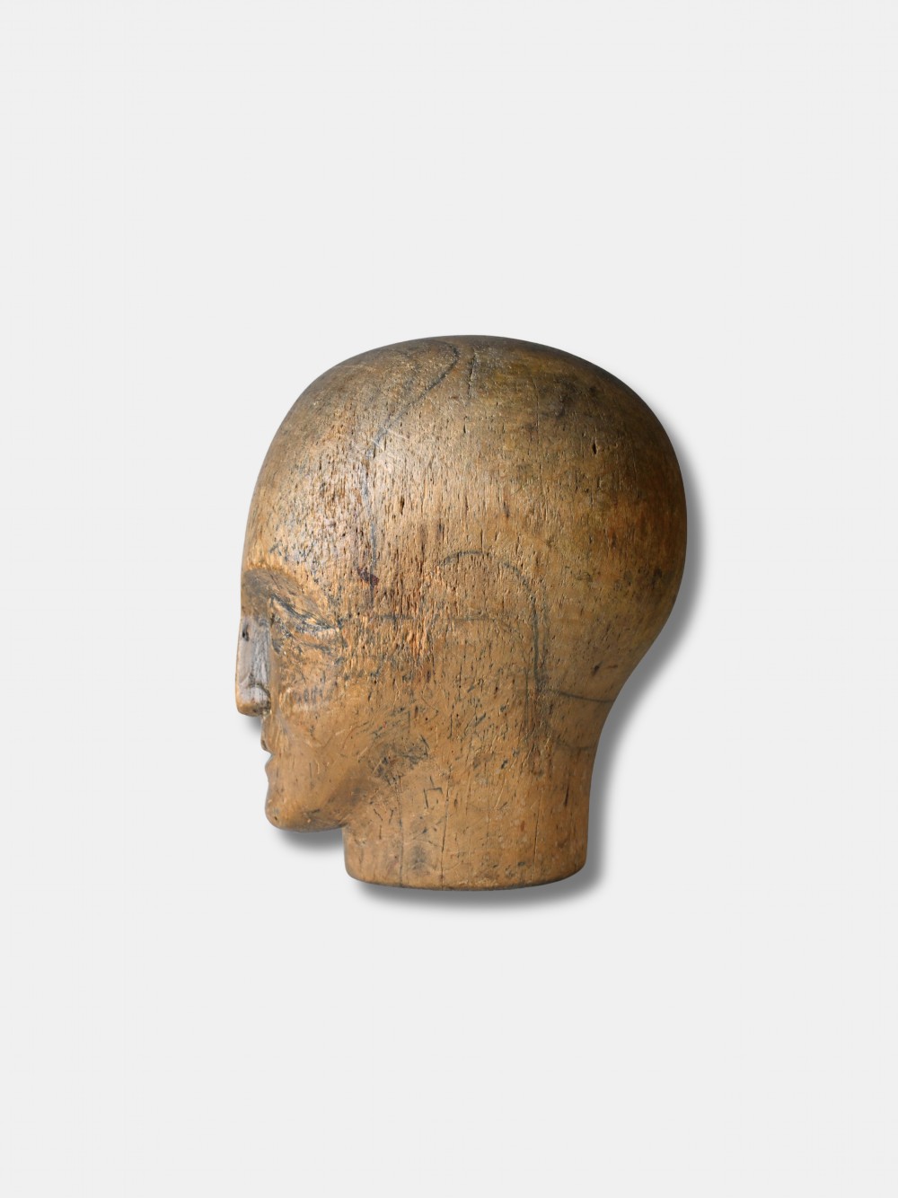 An antique carved wooden millinery head with rendered facial features and a stamped maker inscription on the forehead. View II