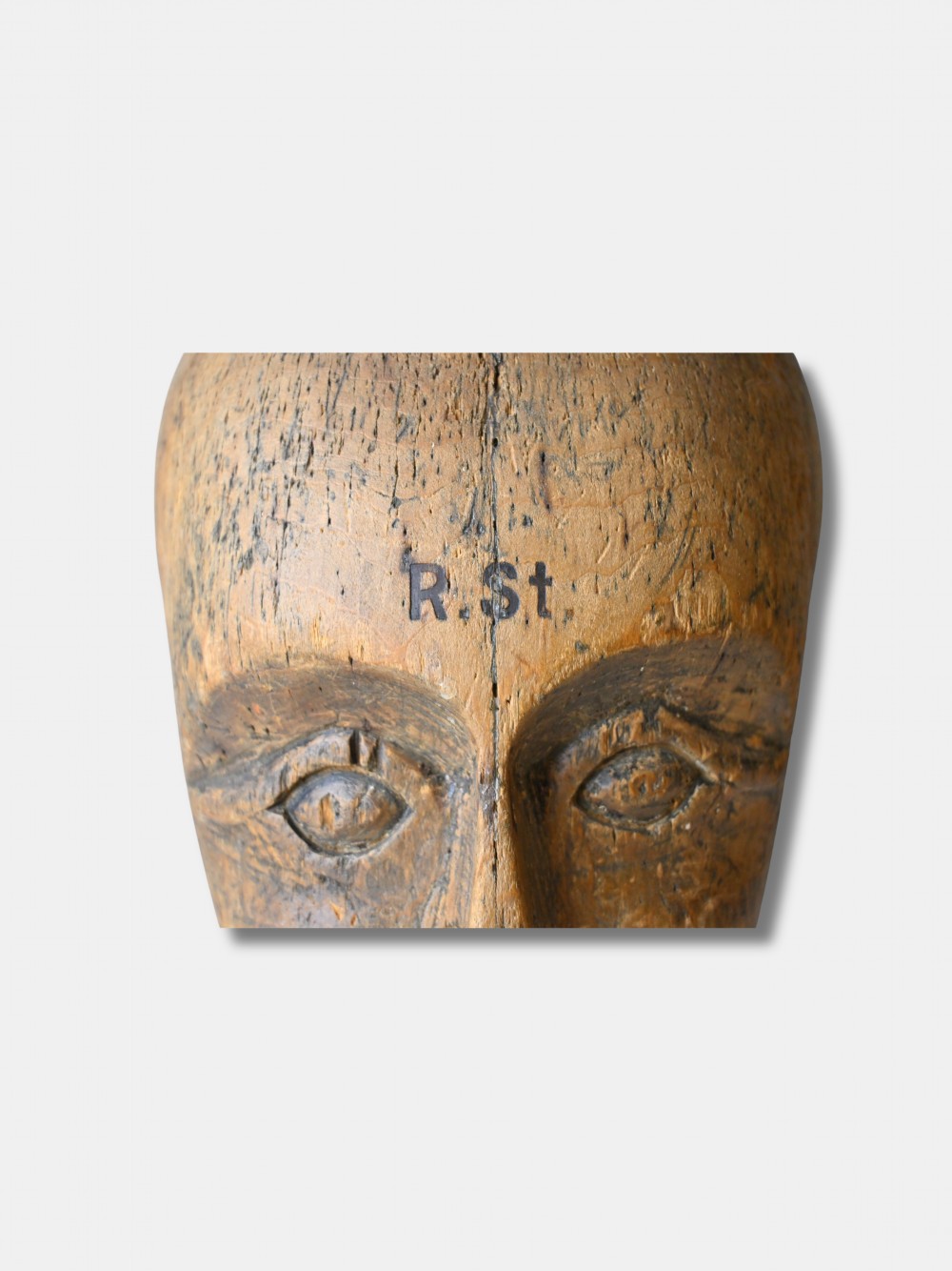 An antique carved wooden millinery head with rendered facial features and a stamped maker inscription on the forehead. View IV