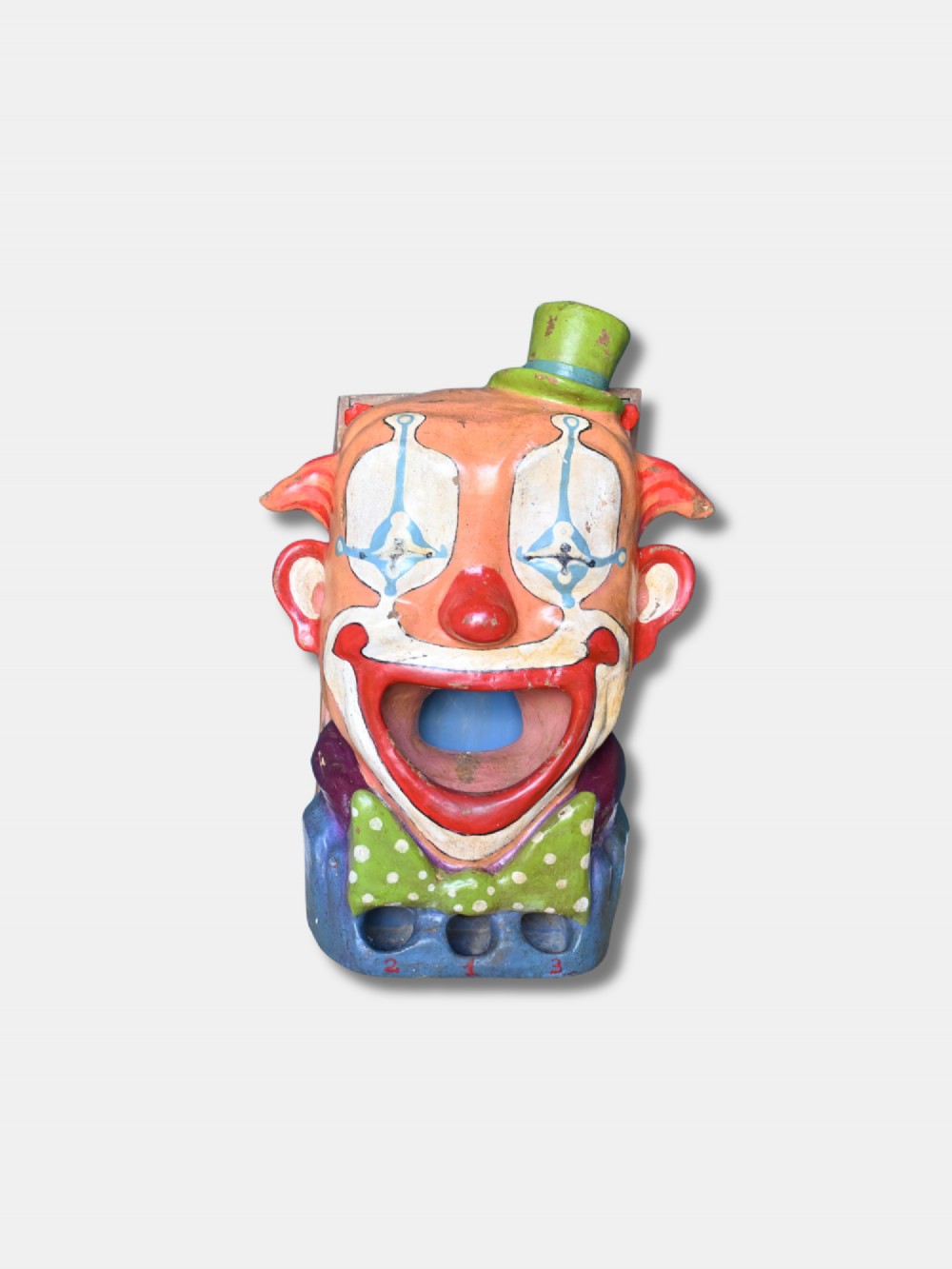 A painted early 20th-century French papier-mache clown head with an open mouth target and green top hat for a fairground ball swallower game.