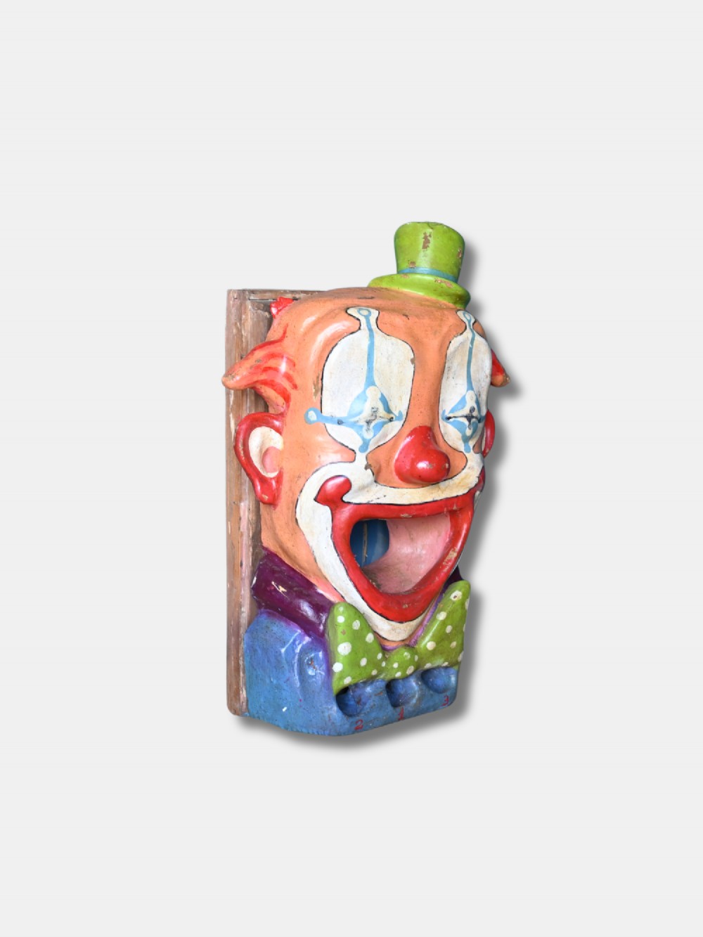 A painted early 20th-century French papier-mache clown head with an open mouth target and green top hat for a fairground ball swallower game. View II