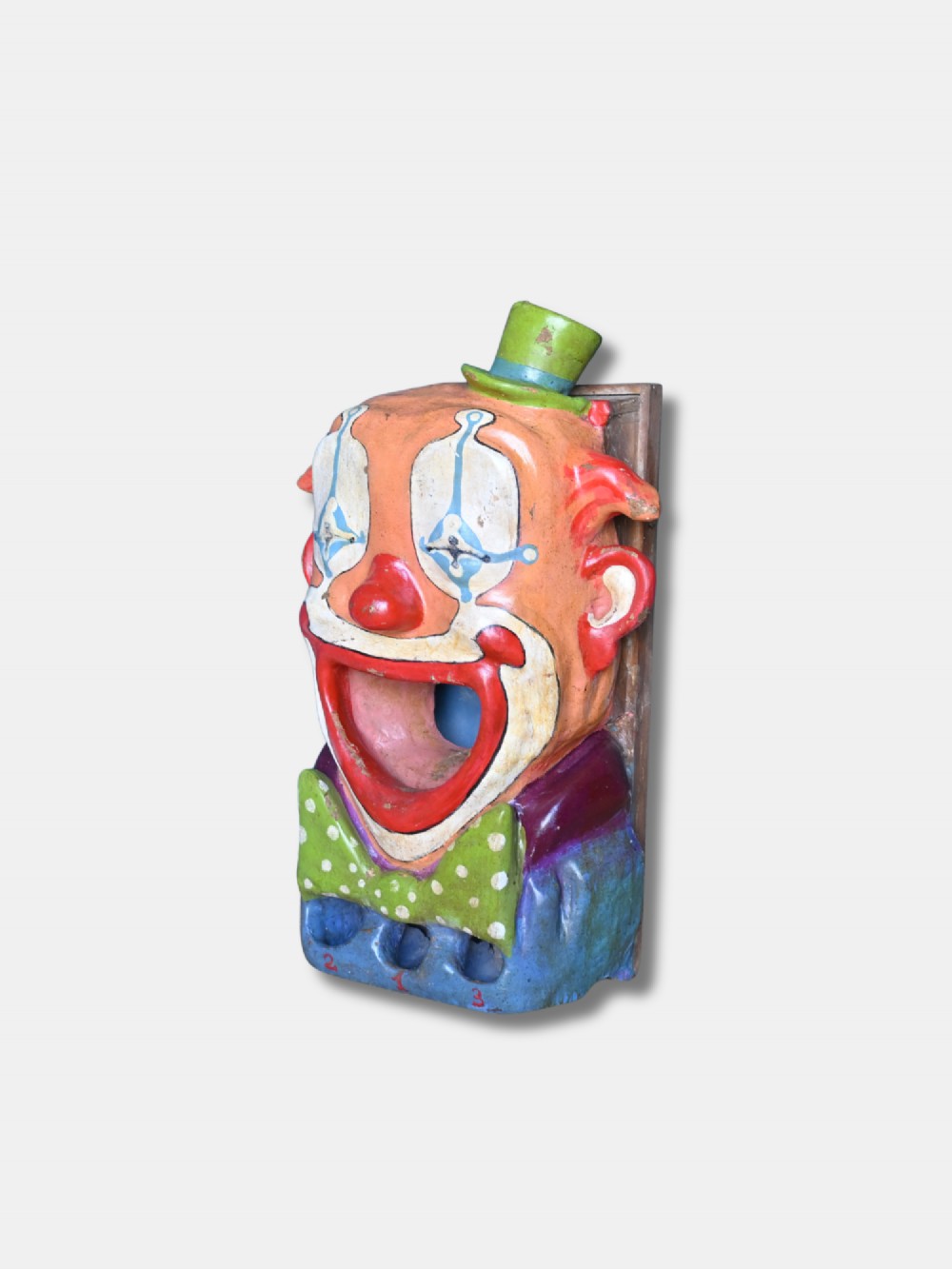 A painted early 20th-century French papier-mache clown head with an open mouth target and green top hat for a fairground ball swallower game. View III