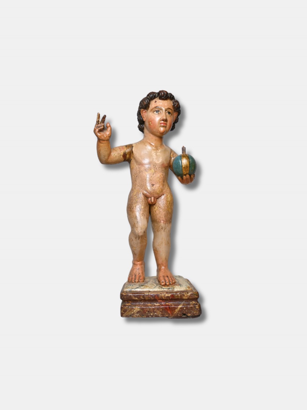 A 17th-century Spanish carved polychrome wood sculpture depicting the standing Infant Jesus holding a blue and gold orb in his left hand and raising his right hand in blessing.