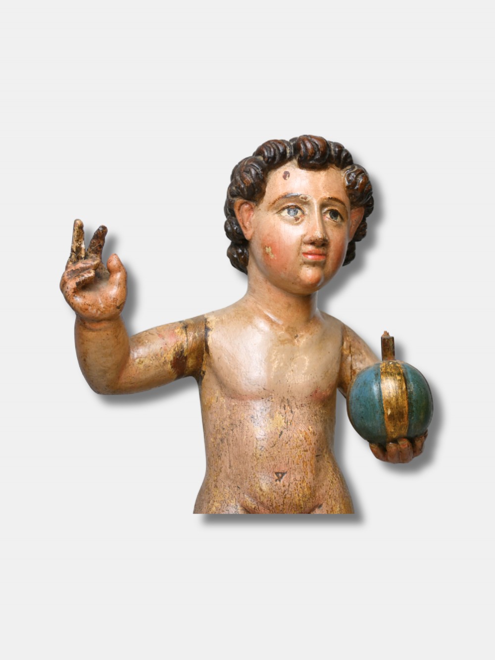 A 17th-century Spanish carved polychrome wood sculpture depicting the standing Infant Jesus holding a blue and gold orb in his left hand and raising his right hand in blessing. View V