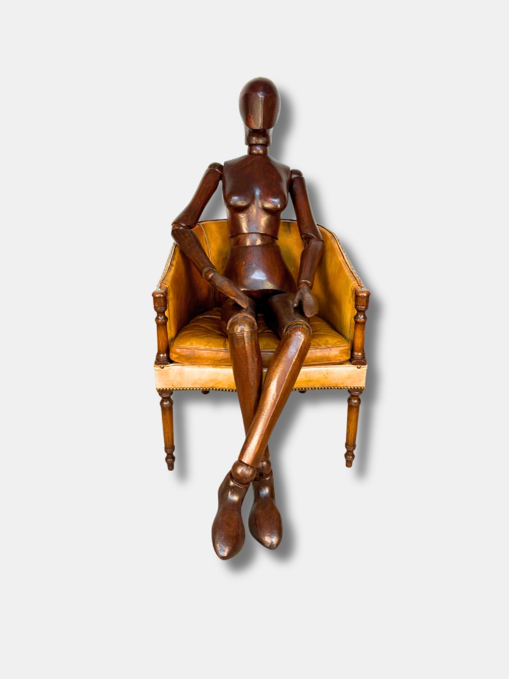 A life-size articulated female wooden lay figure depicted in a seated position with legs crossed and one hand raised. View II