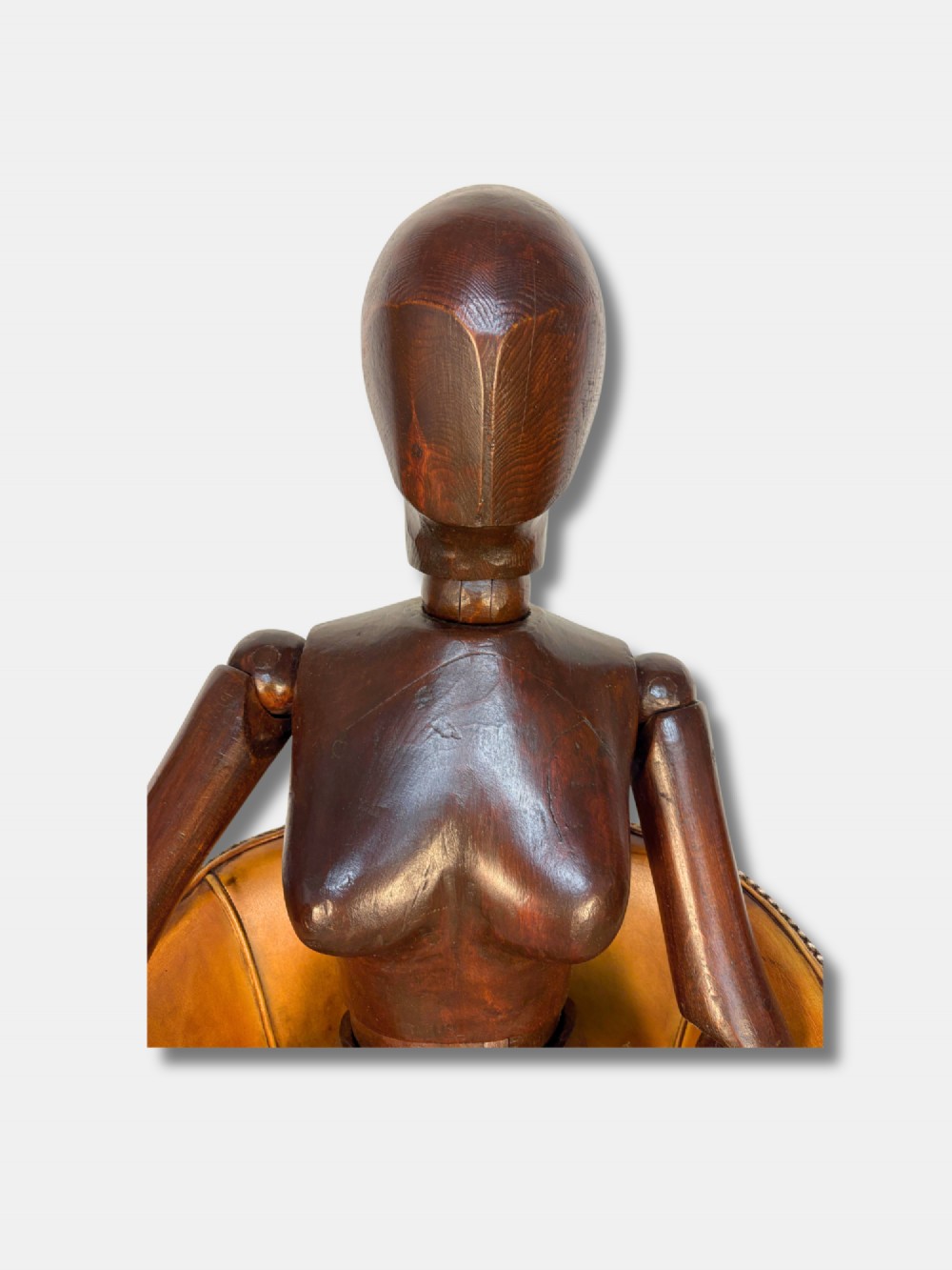 A life-size articulated female wooden lay figure depicted in a seated position with legs crossed and one hand raised. View III