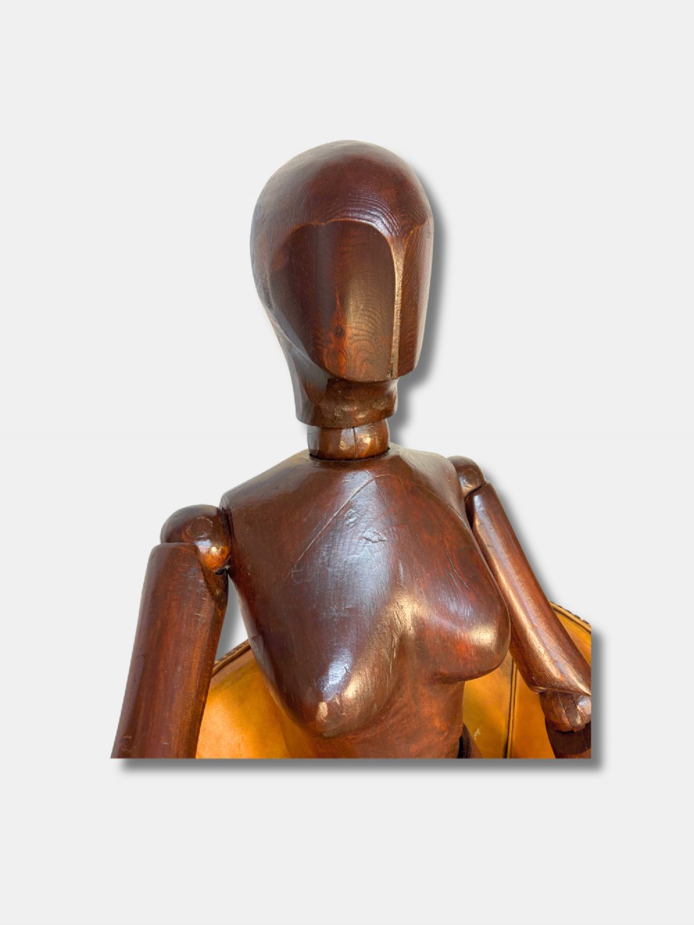A life-size articulated female wooden lay figure depicted in a seated position with legs crossed and one hand raised. View V