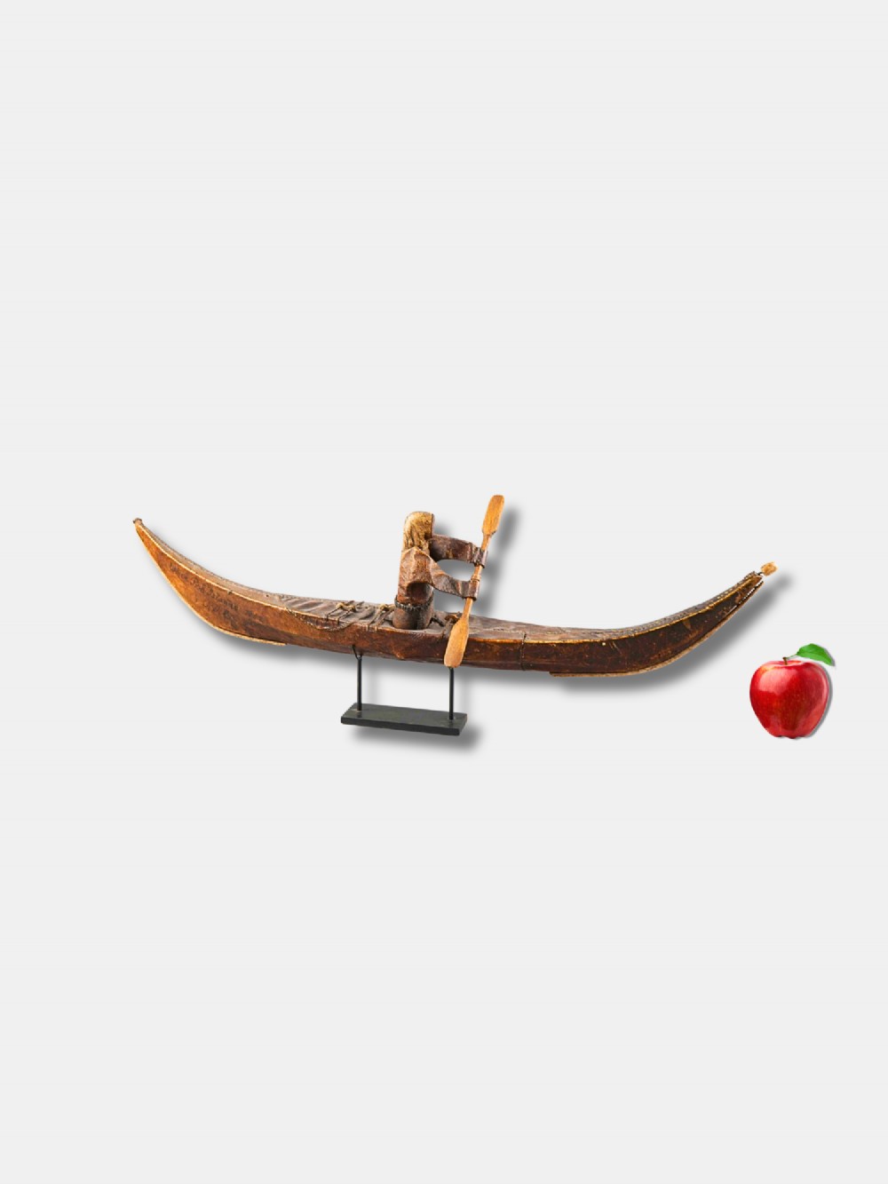 An 1882 Inuit model kayak crafted from tanned seal skin over a frame, featuring a central carved paddler figure holding a paddle, mounted on a modern black display stand. View II
