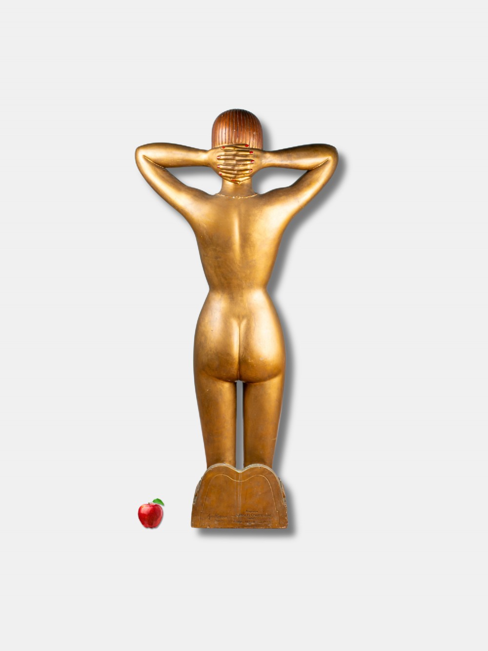 A gold-painted Art Deco plaster female figure kneeling with arms behind her head, mounted on a base inscribed with Charmereine Paris. View II