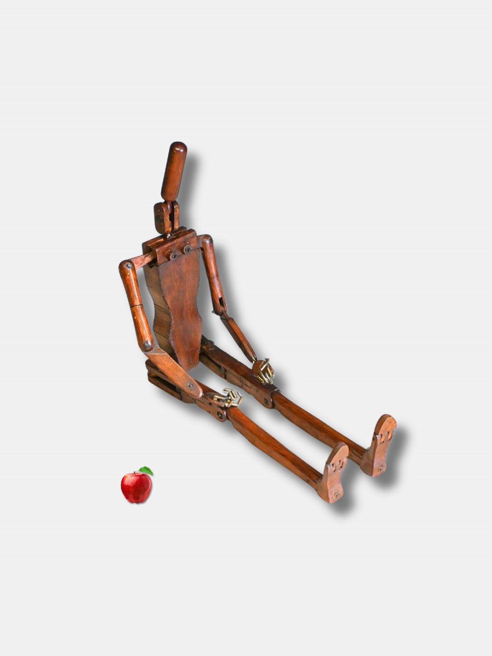 A carved wooden articulated lay figure shown seated with jointed limbs and brass joint fittings.