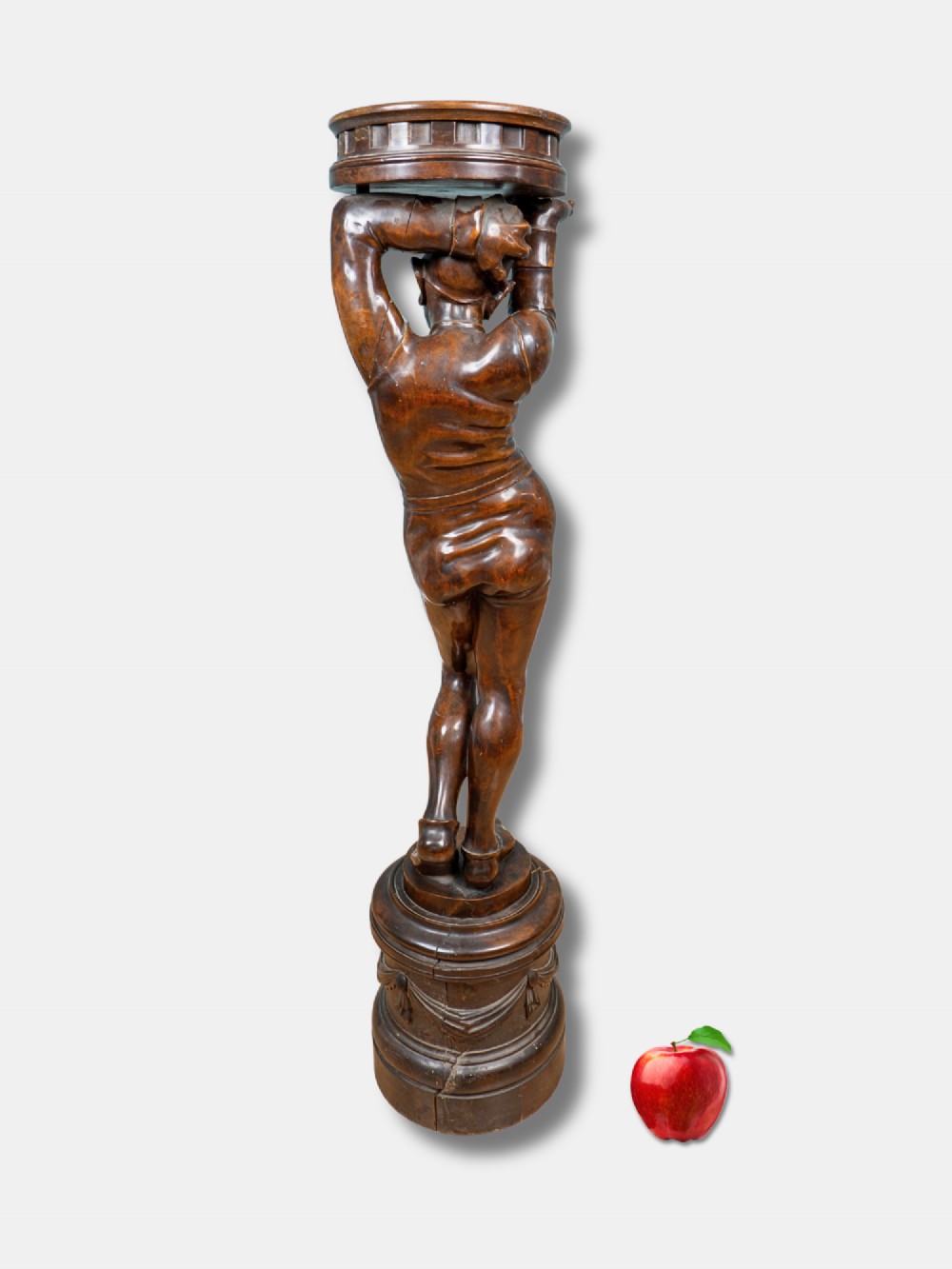 An Italian 19th-century hand-carved dark wood torchere stand depicting a jester figure holding a circular top on a moulded plinth base. View II