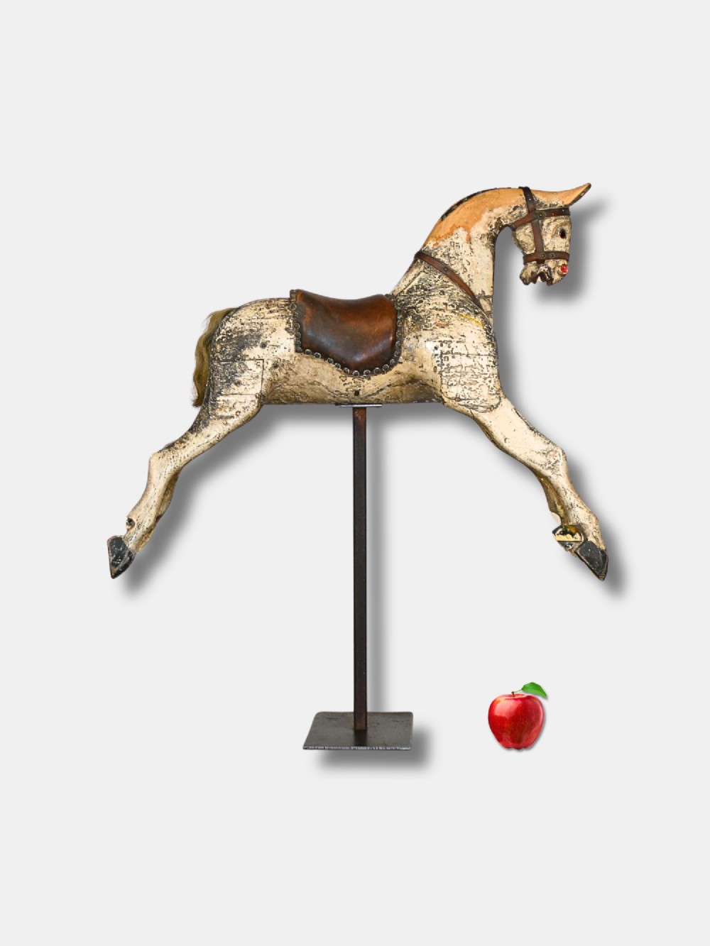A carved 19th-century wooden rocking horse figure with distressed cream paint and a leather saddle, mounted on a dark metal display stand.