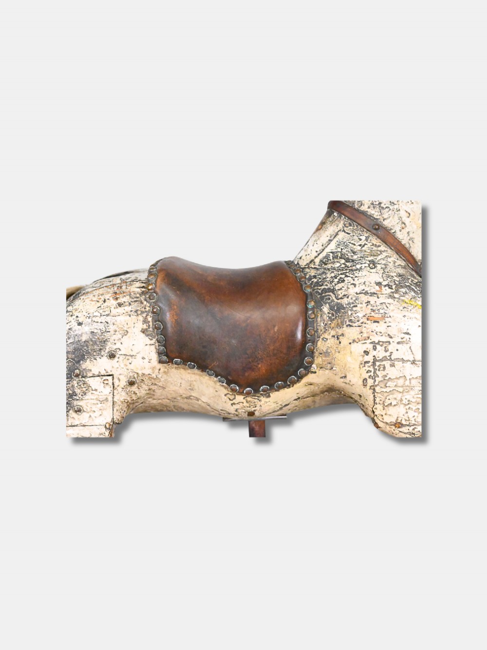 A carved 19th-century wooden rocking horse figure with distressed cream paint and a leather saddle, mounted on a dark metal display stand. View II