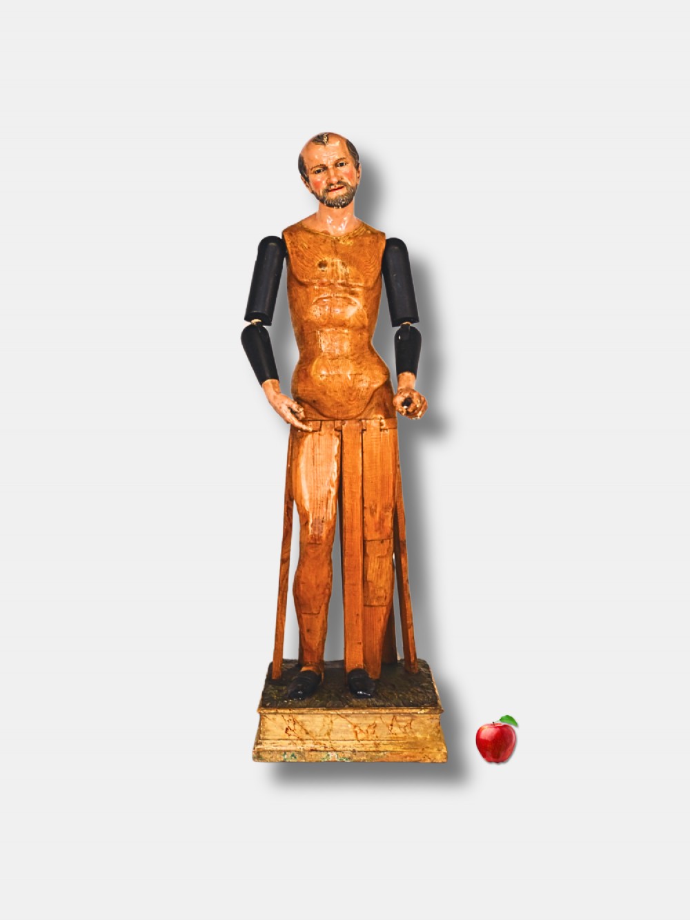 A life-sized 19th-century carved wooden Italian Santos figure with dark articulated arms, polychrome facial features, and a stepped timber base.