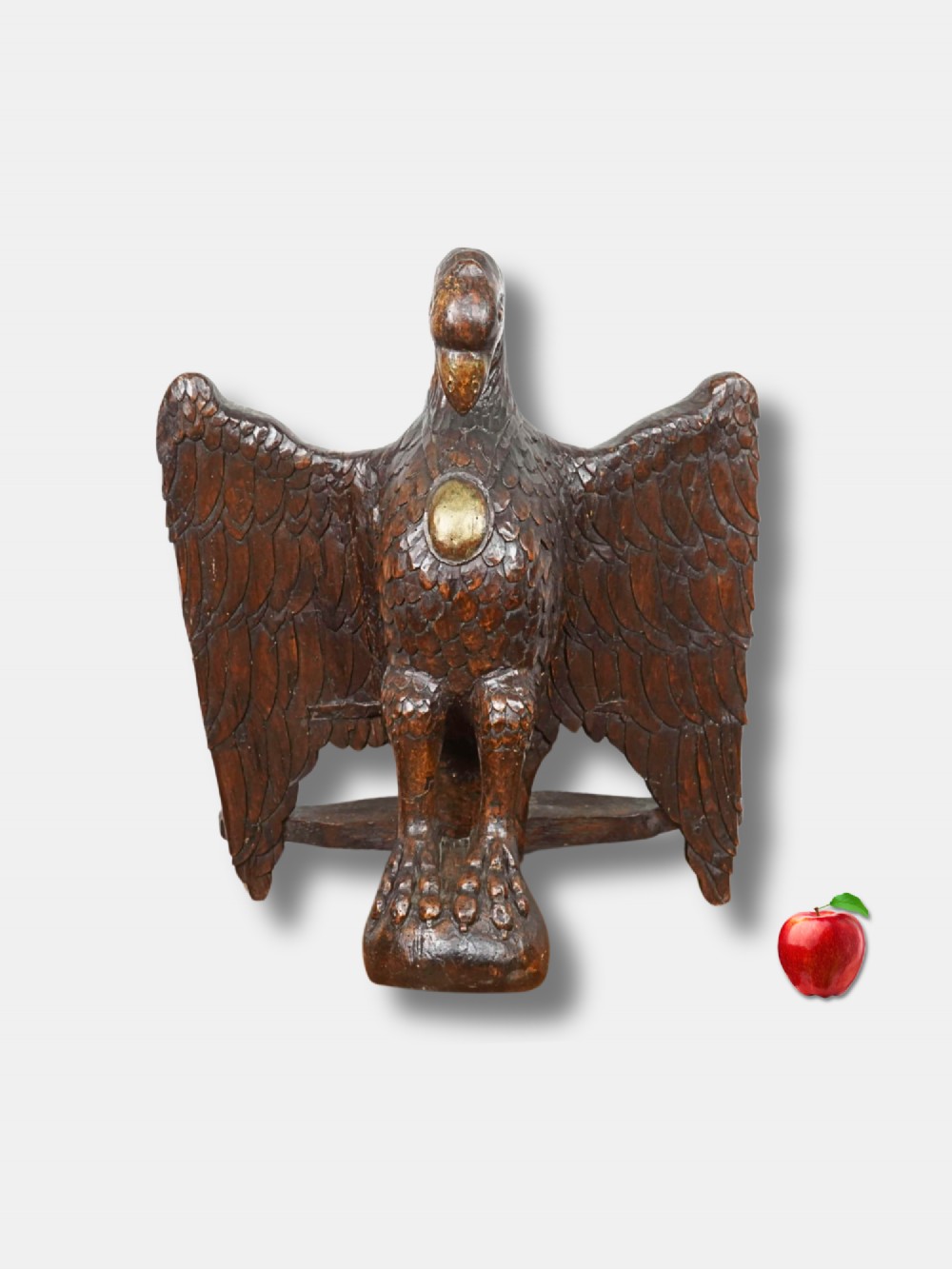 An eighteenth-century carved oak lectern depicting an eagle with outstretched wings and a small gilded oval medallion on its chest.