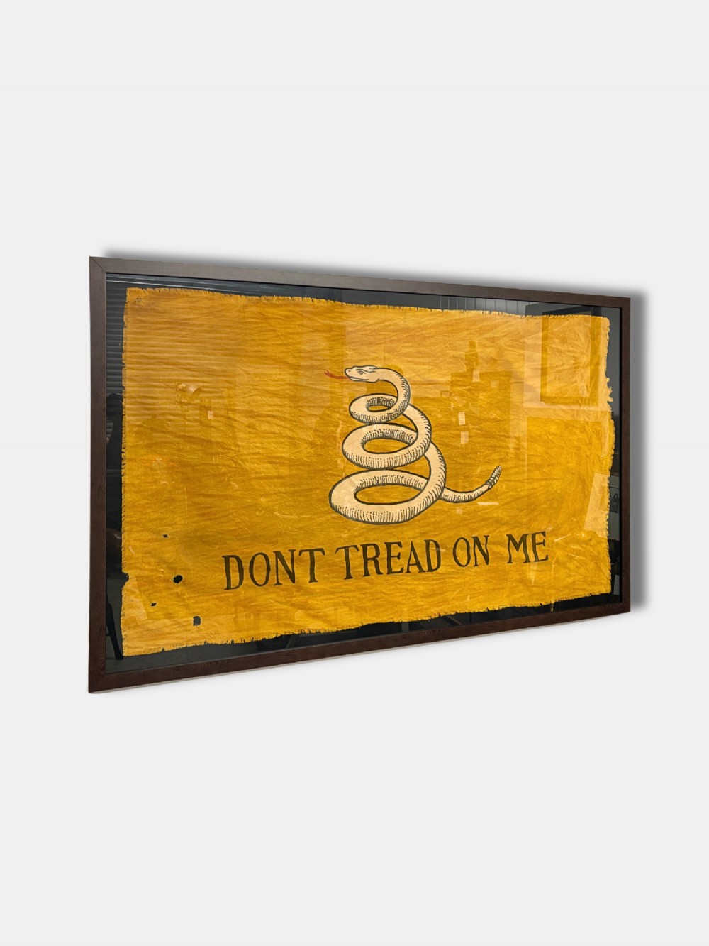 A framed yellow antique Gadsden flag displaying a coiled rattlesnake motif above black lettering reading DONT TREAD ON ME.