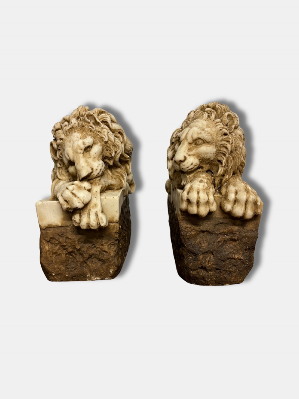 A pair of late nineteenth-century carved alabaster lion sculptures depicted resting atop rustic stone bases, after Antonio Canova.
