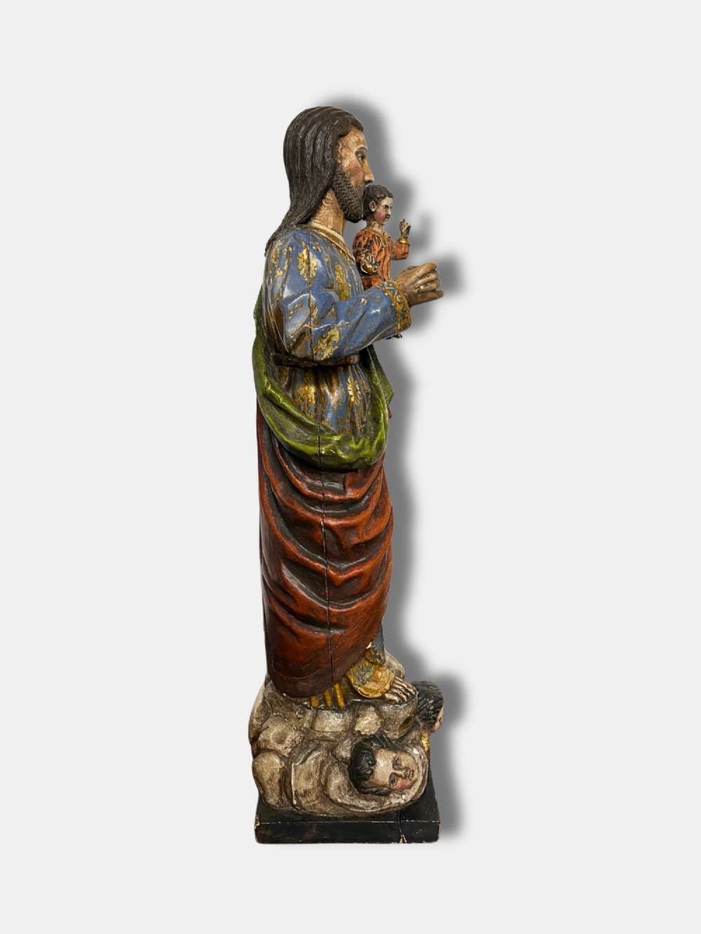 An 18th-century Peruvian carved polychrome wood statue of Saint Joseph holding the infant Jesus standing on a base decorated with cherub heads. View II