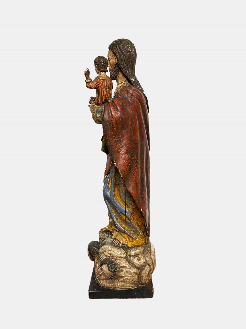 An 18th-century Peruvian carved polychrome wood statue of Saint Joseph holding the infant Jesus standing on a base decorated with cherub heads. View IV