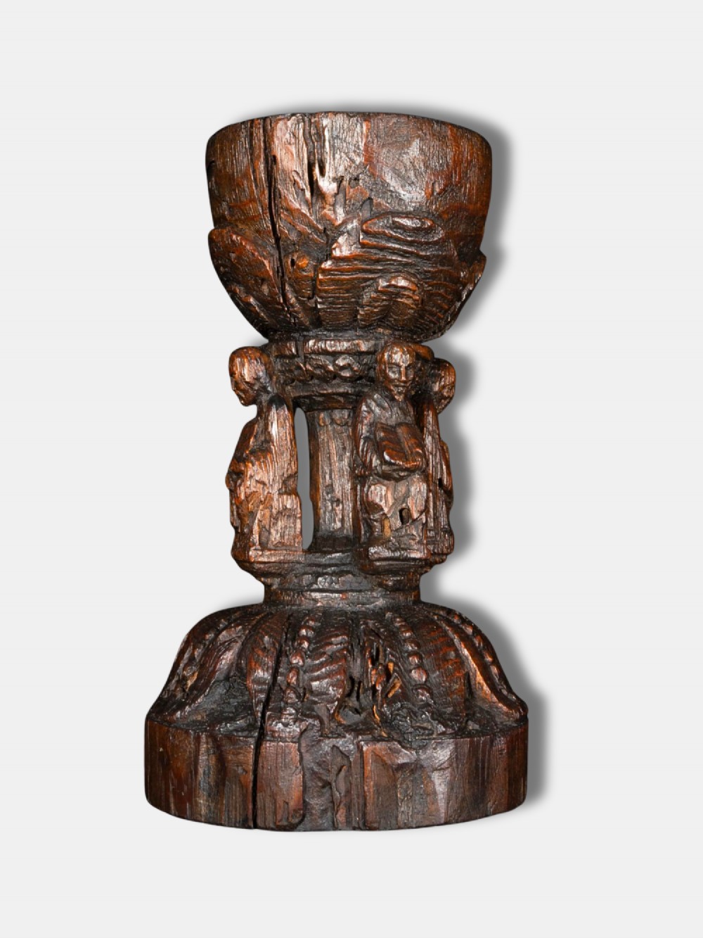 A 16th-century dark carved oak chalice featuring sculpted human figures around the stem and carved leaf motifs on the base and bowl. View II
