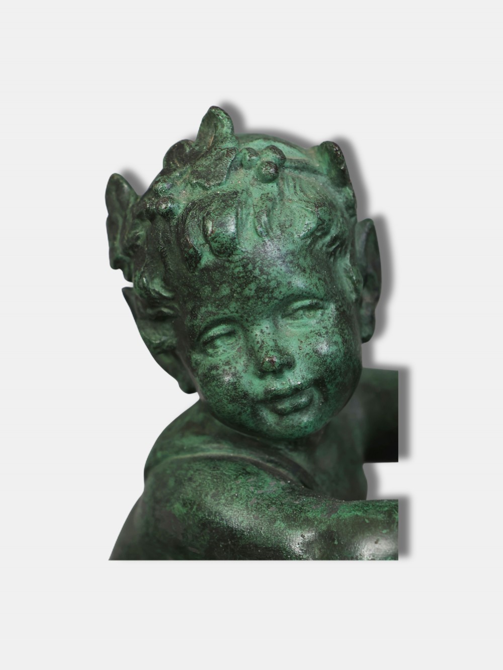 A green patinated bronze sculpture depicting a young faun interacting with a rearing goat, mounted on a rectangular marble base. View III