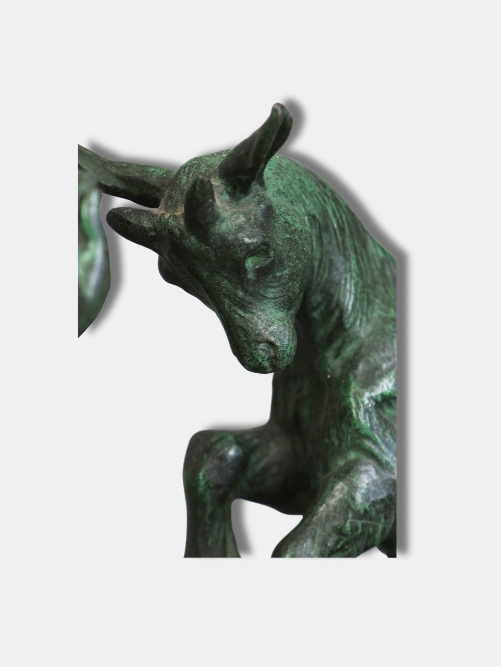 A green patinated bronze sculpture depicting a young faun interacting with a rearing goat, mounted on a rectangular marble base. View IV