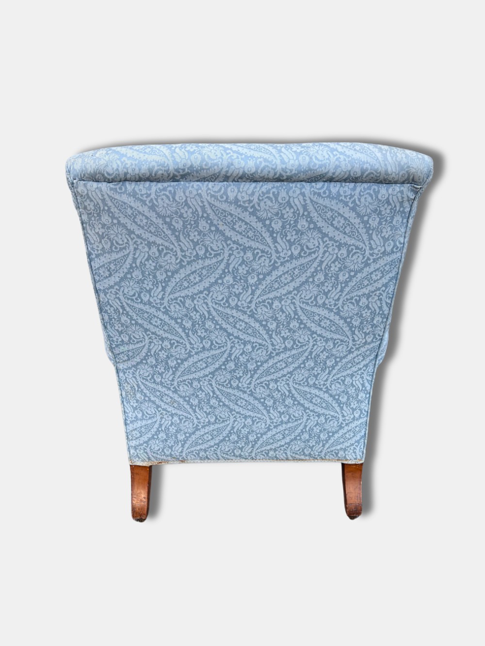 A late Victorian Howard and Sons armchair upholstered in light blue paisley fabric, featuring button-tufted backrest detail, rolled arms, and turned wooden front legs with brass castors. View IV
