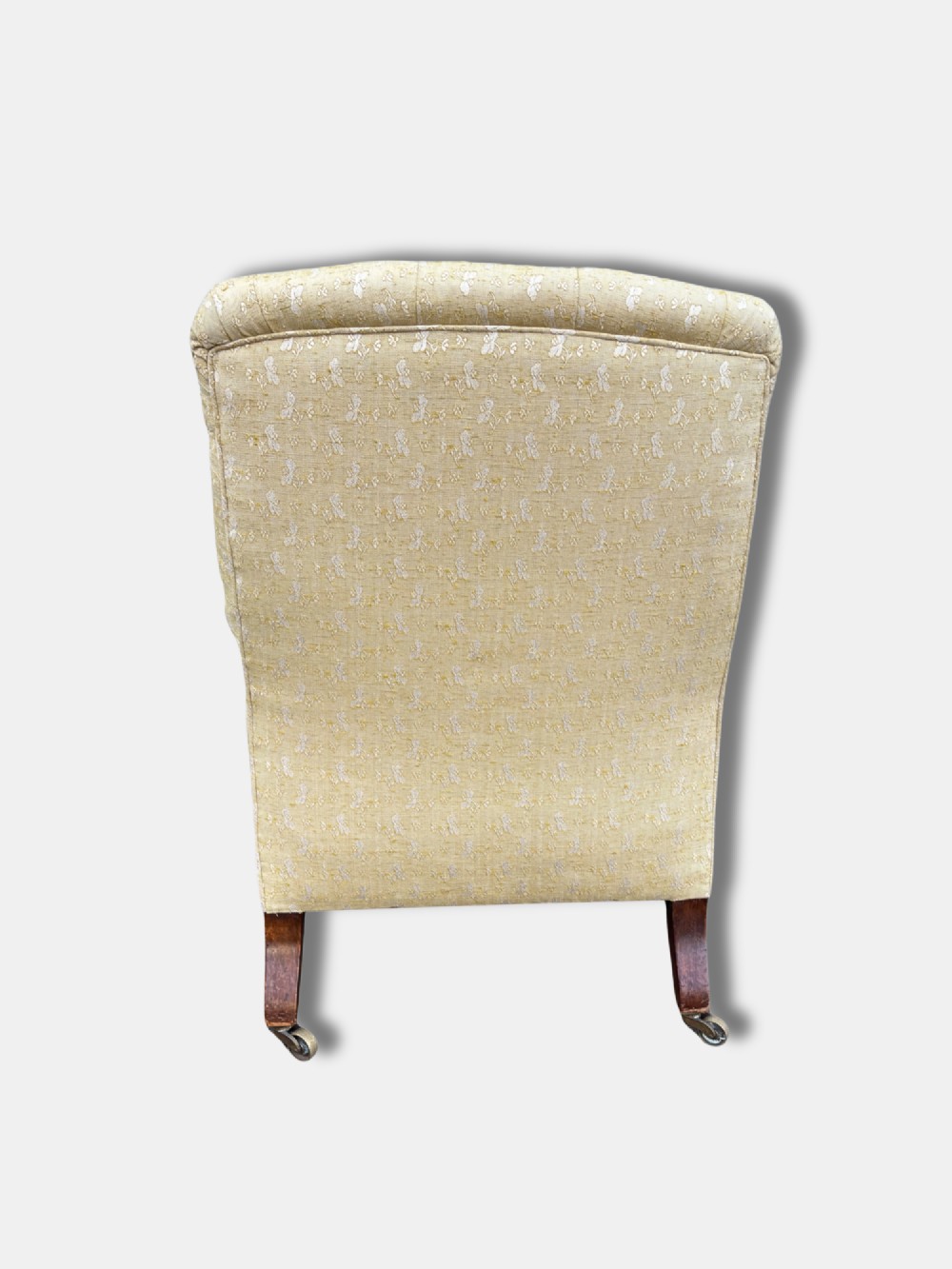 A Victorian armchair upholstered in pale yellow patterned fabric featuring a deep-buttoned backrest, scrolled armrests, and turned wood legs with brass castors. View IV
