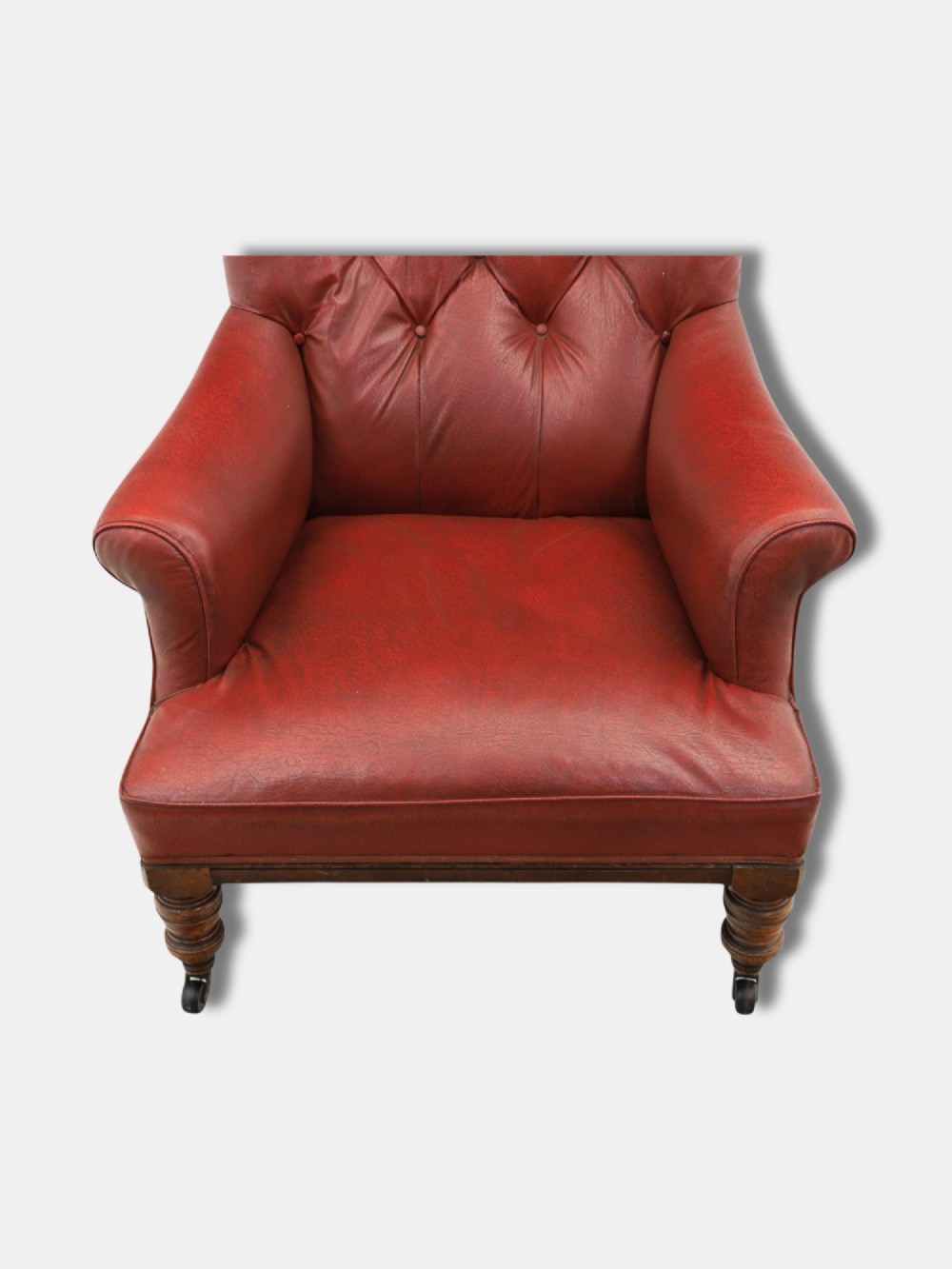 A pair of 1920s English armchairs upholstered in red oxblood rexine with deep buttoning and turned wooden legs on castors. View VII