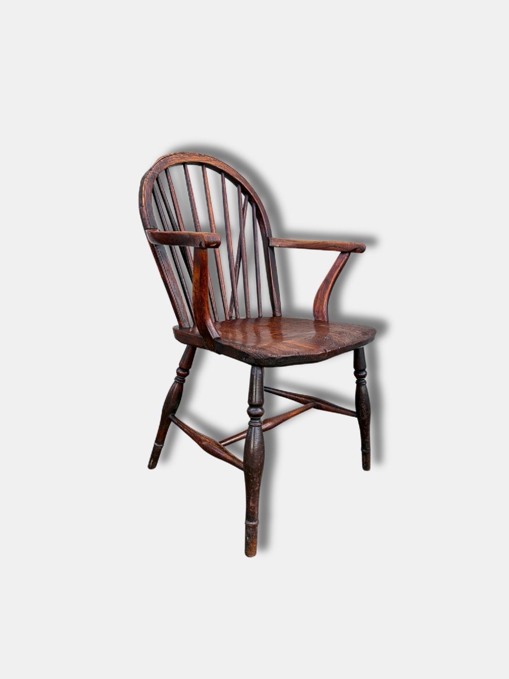 A dark brown antique Thames Valley Windsor armchair made of timber featuring a hoop back with spindles, curved armrests, a shaped solid seat, and turned legs. View II