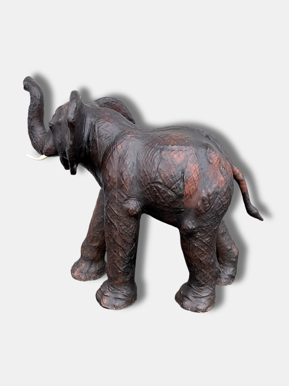 An extra-large antique dark brown leather elephant bench featuring a raised trunk, detailed hide texture, glass eyes, and short tusks. View III
