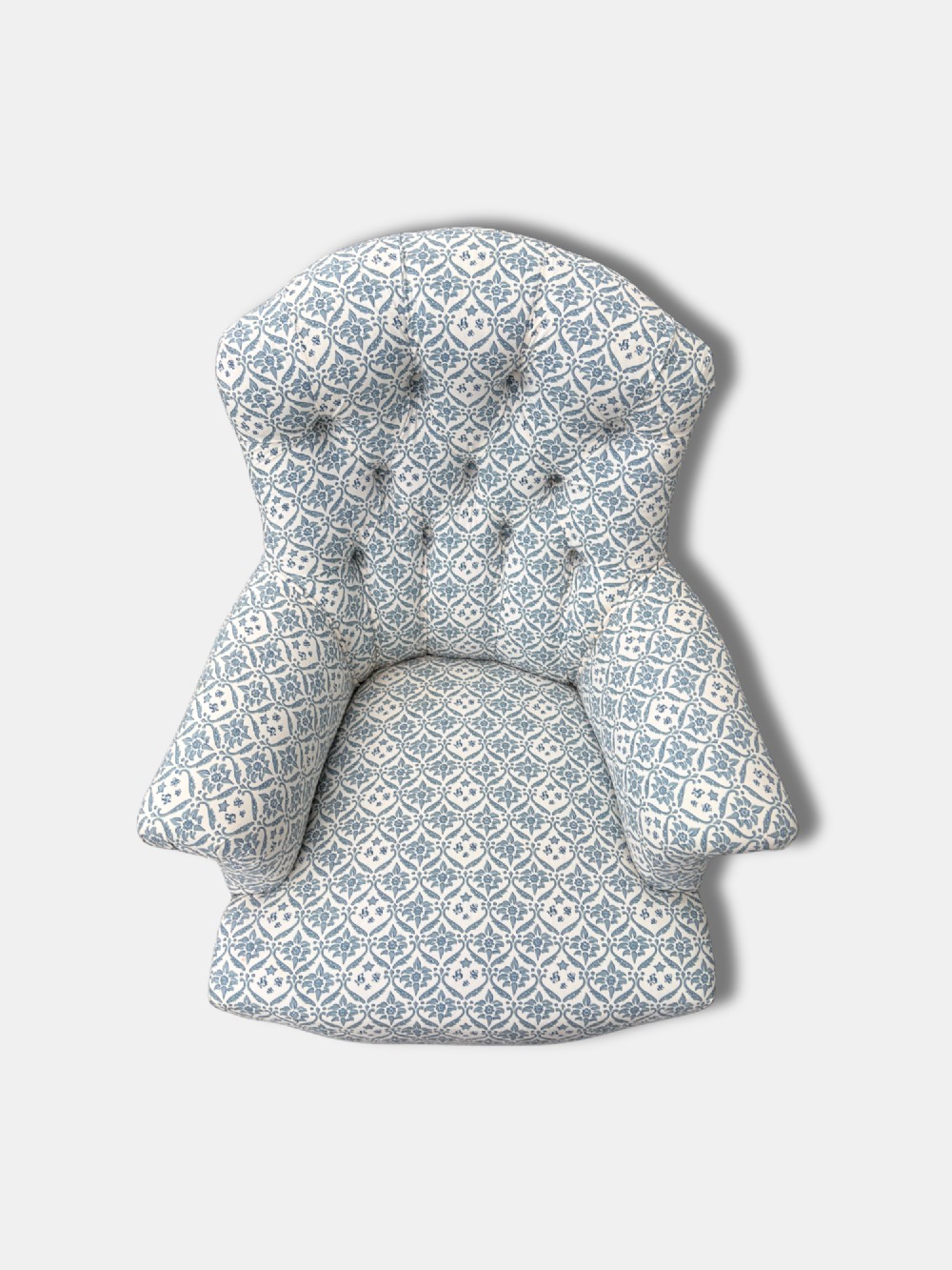A late Victorian button back armchair upholstered in blue and white botanical patterned fabric, featuring turned wooden front legs on brass castors. View IV