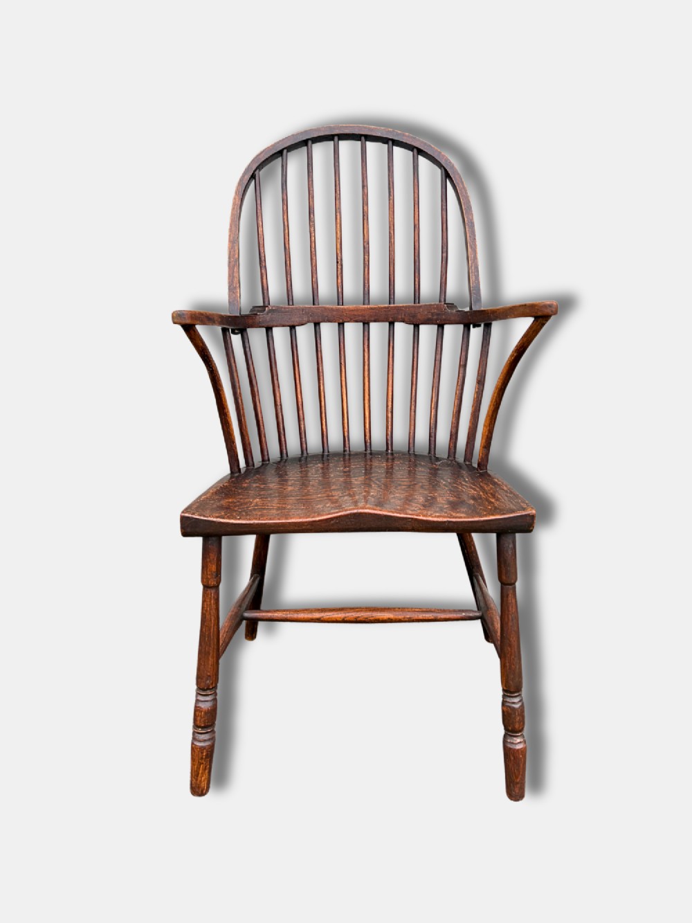 A dark timber hoop back Windsor armchair featuring vertical spindles, bentwood arm supports, a saddle seat, and turned legs with an H-stretcher. View II